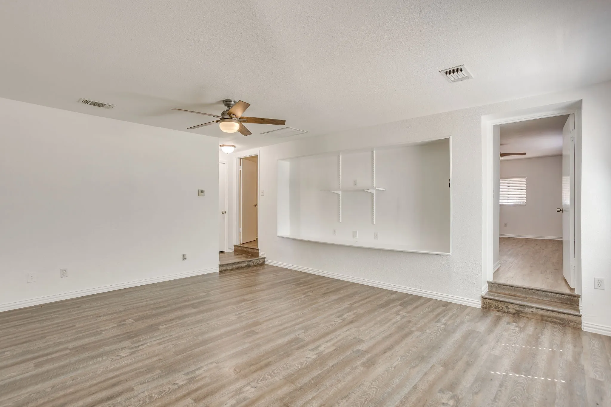 Wood-finish flooring throughout, ceiling fan with integrated lighting, and built-in shelving