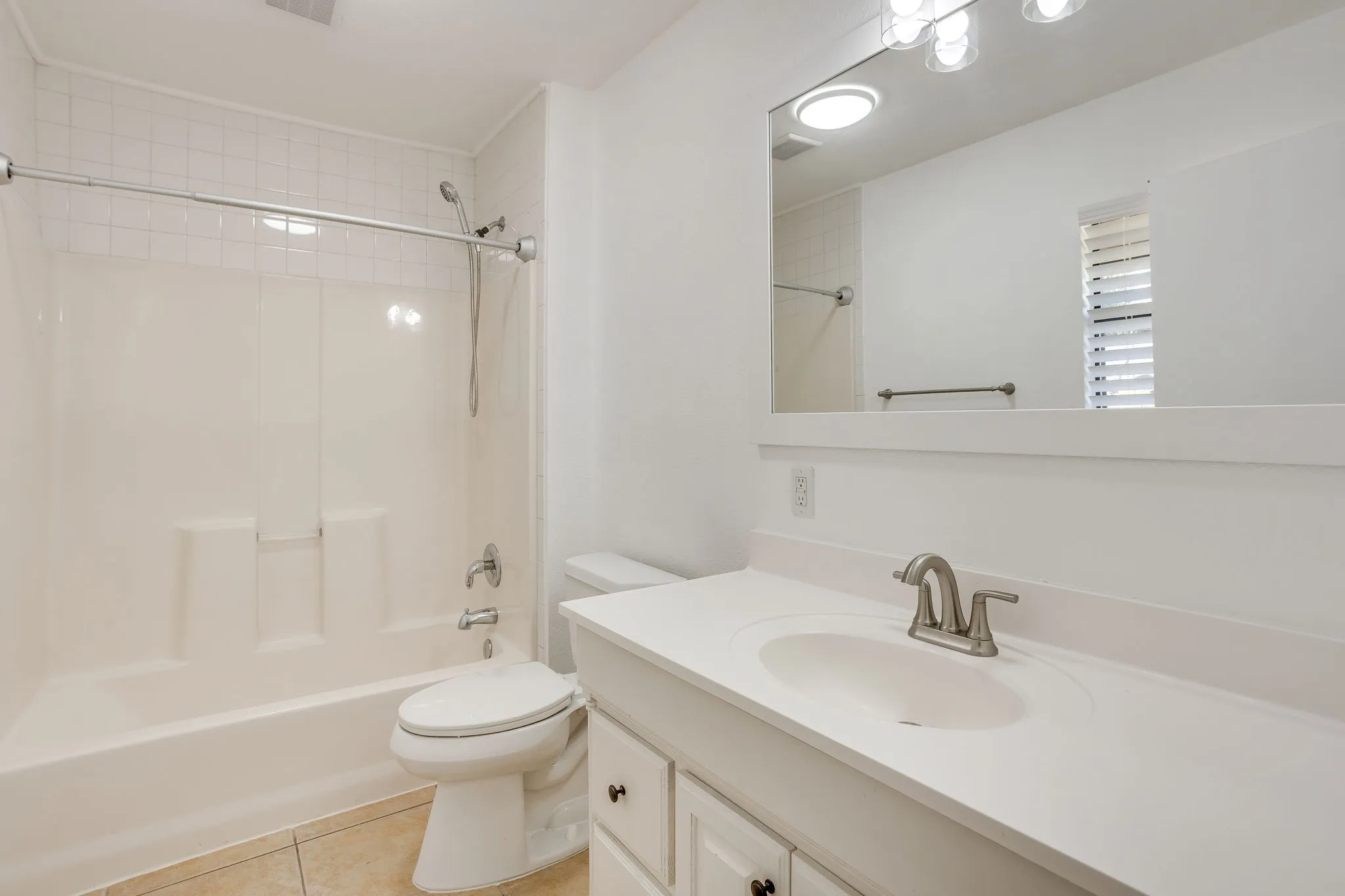 Bathroom featuring a white vanity with integrated sink, brushed nickel faucet, and overhead lighting