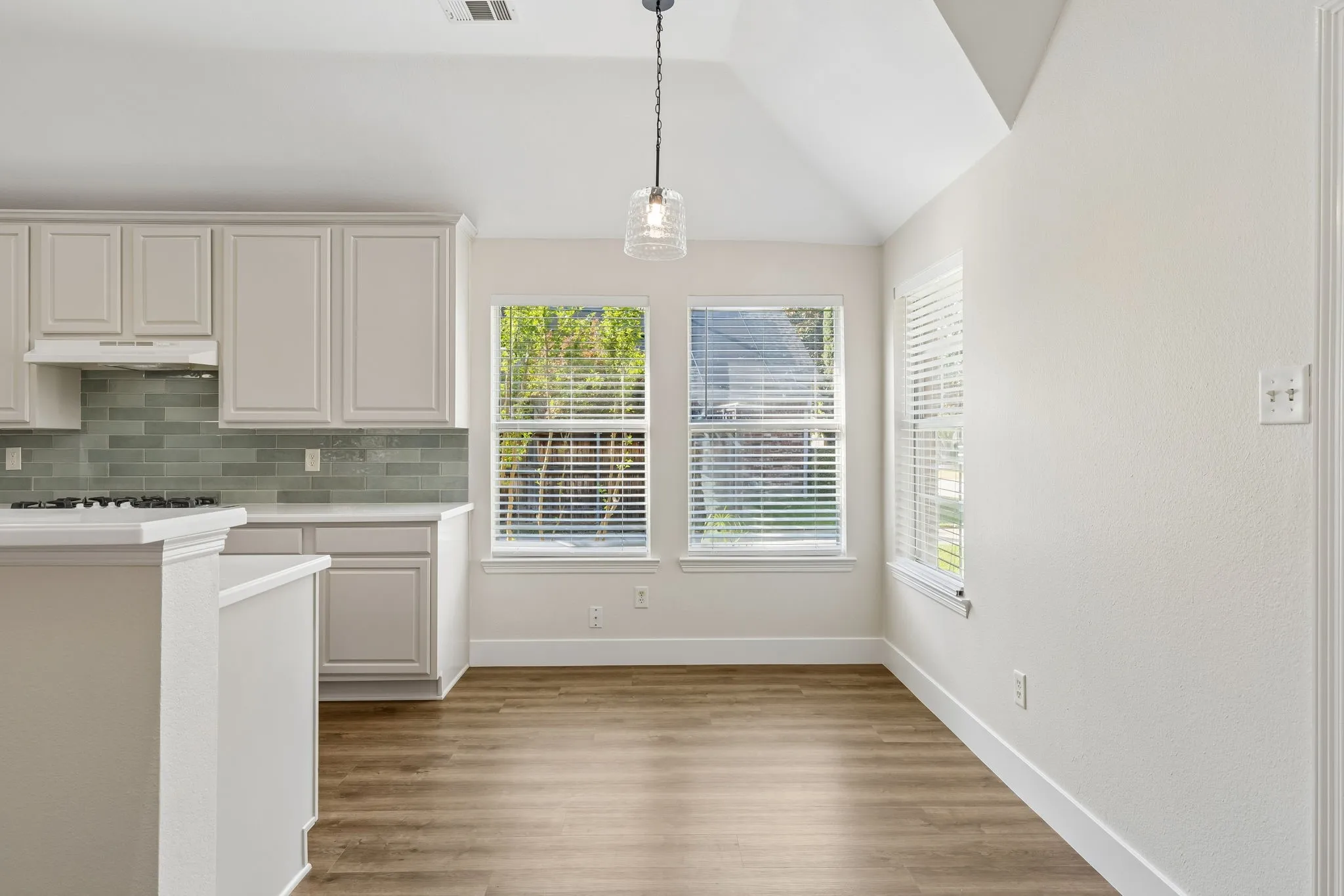 Kitchen with light cabinetry, tiled backsplash, and wood-finish flooring