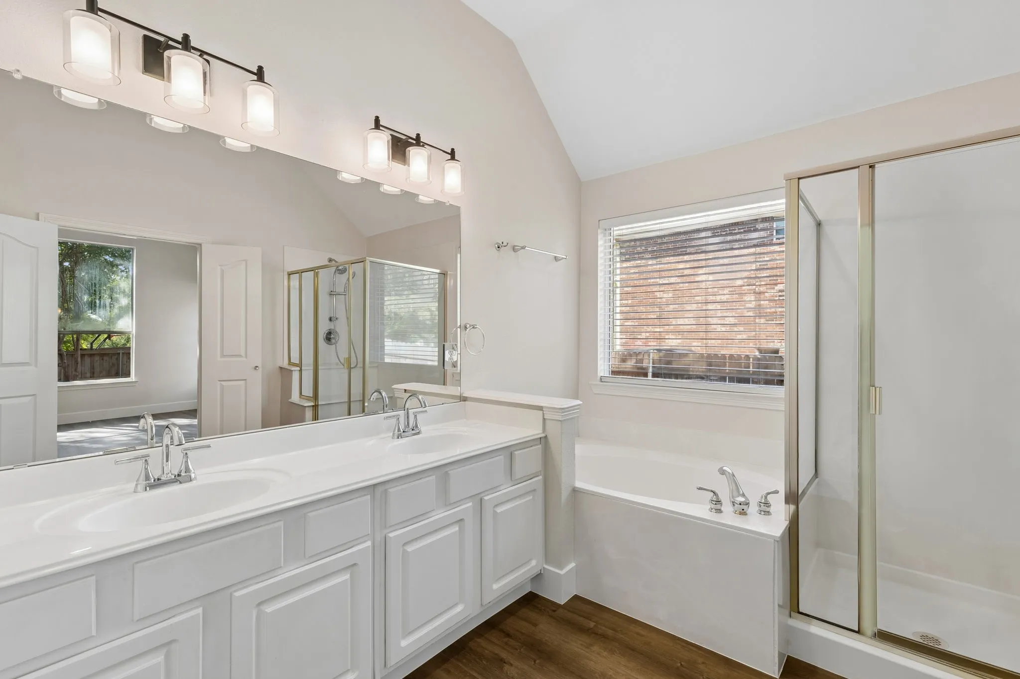 Dual vanity with white cabinetry, built-in soaking tub, and enclosed shower with clear glass door