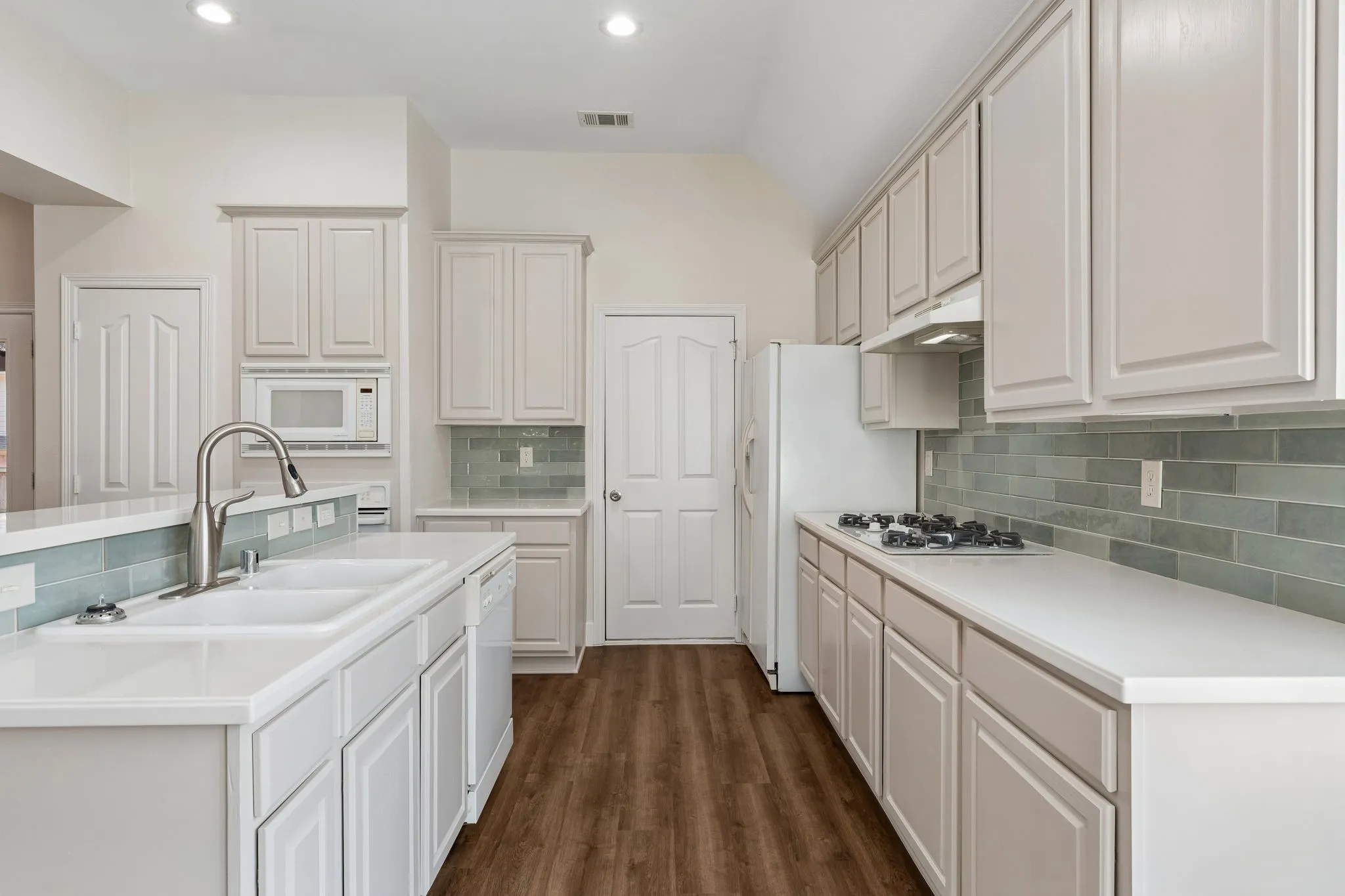 Kitchen featuring recessed lighting, white cabinetry, a dual basin sink with a gooseneck faucet, light countertops, and a subway tile backsplash