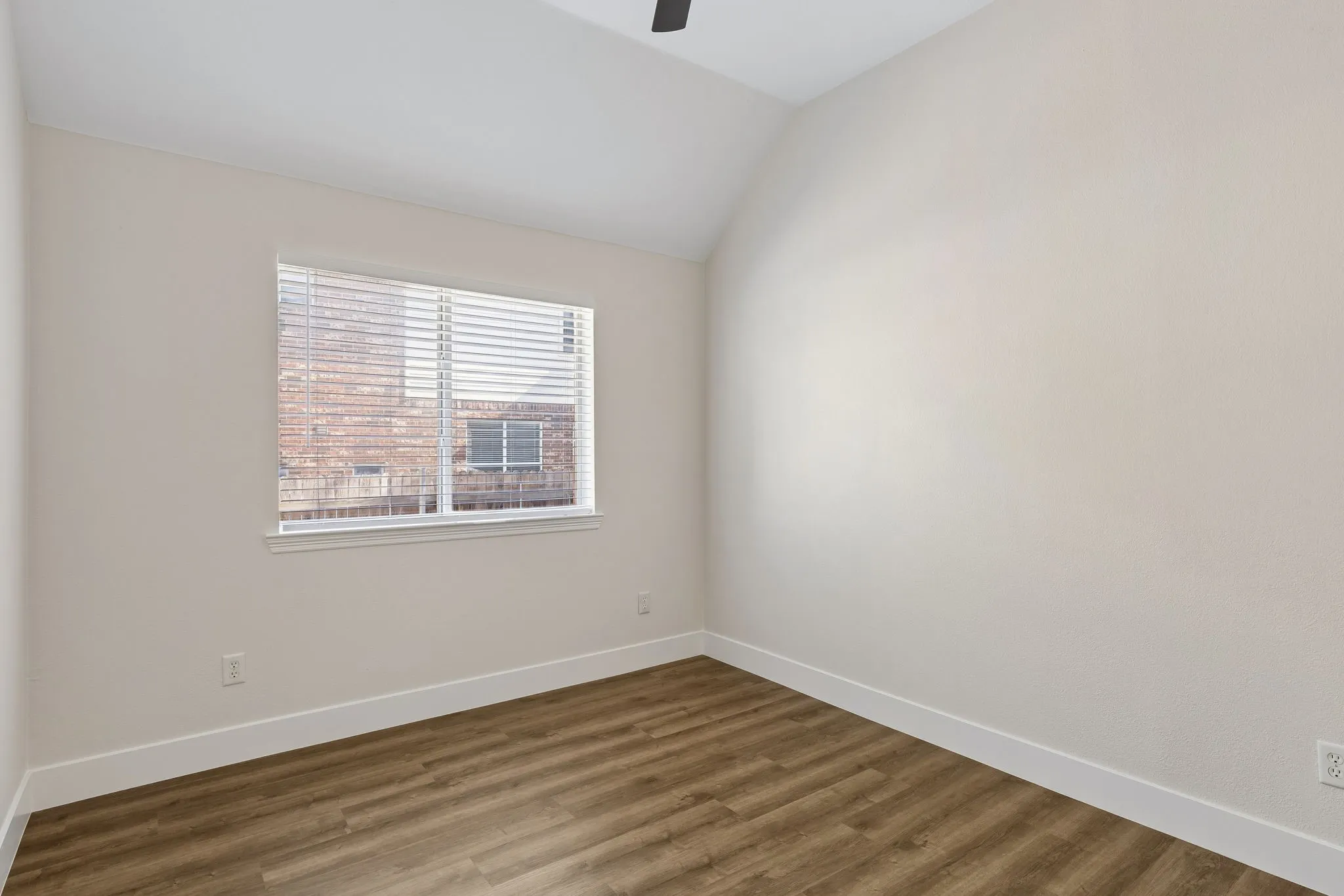 Vaulted ceiling, wood-finish flooring, white window blinds, and a ceiling fan