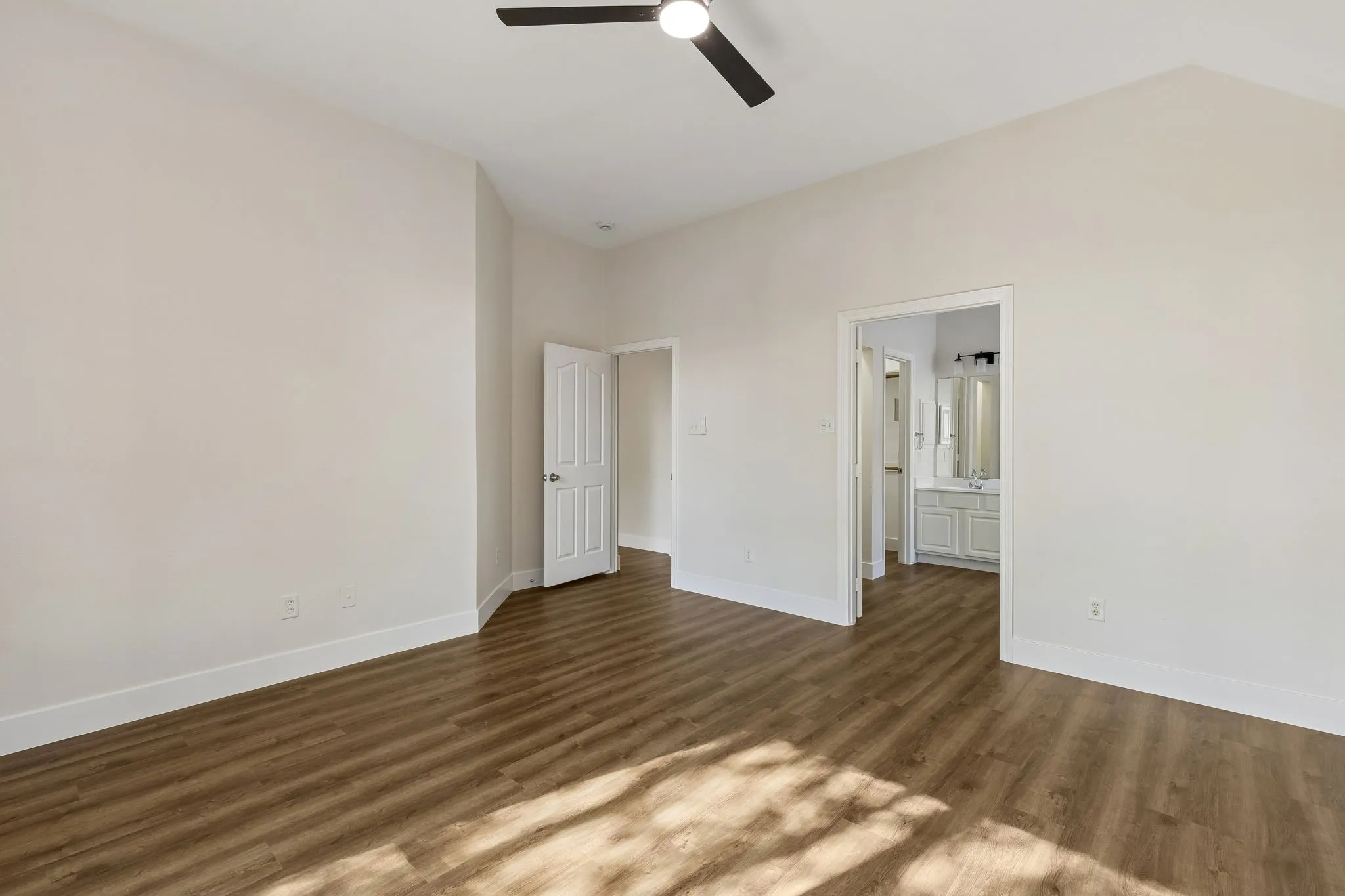 Vaulted ceiling with a ceiling fan, wood-finish flooring, and white interior doors