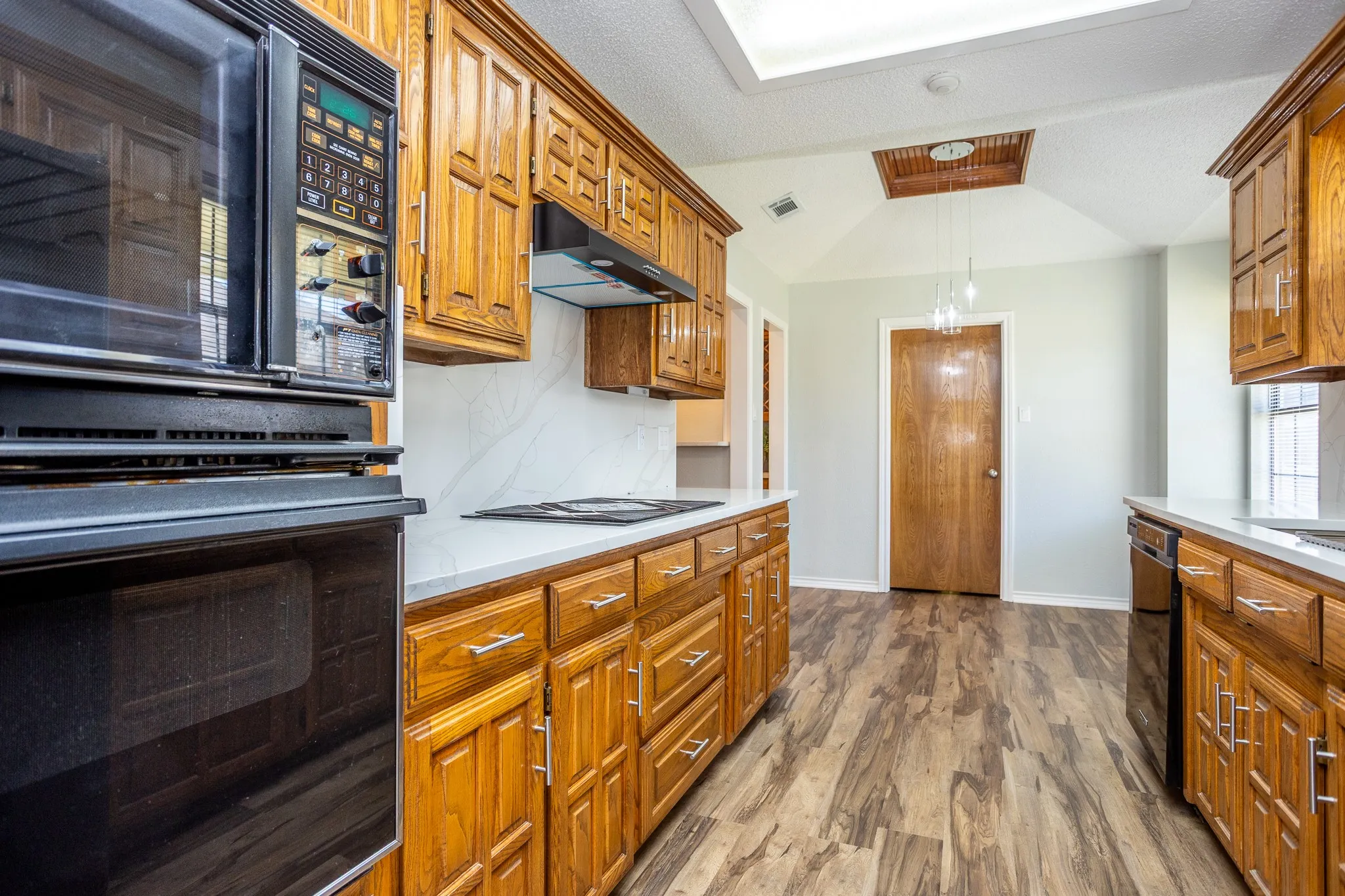 OVEN, MICROWAVE AND GLASS COOK TOP.  PICTURE SHOWS CEILING TREATMENT IN BREAKFAST NOOK. DOOR GOES TO UTILITY ROOM, PANTRY CLOSET AND TO GARAGE.
