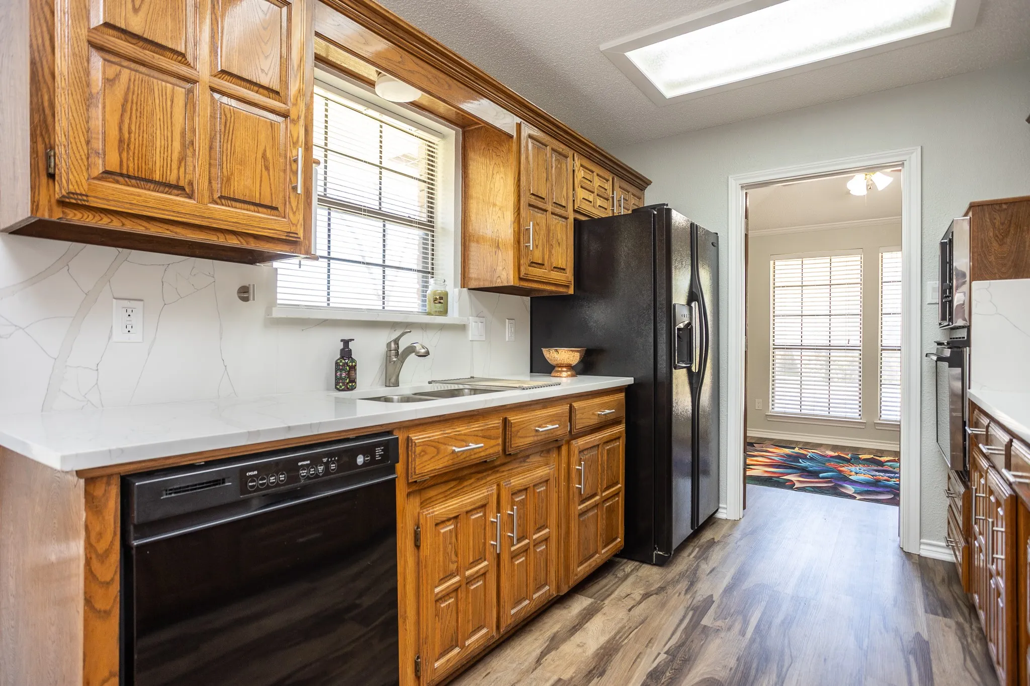 CUSTOM CABINETS IN GREAT CONDITION. GRANITE COUNTERS AND BACK SPLASH. STAINLESS SINK. DISHWASHER.  REFRIGERATOR REMAINS.  SHOWS FORMAL DINING AREA AND DOUBLE WINDOWS. SKYLIGHT.