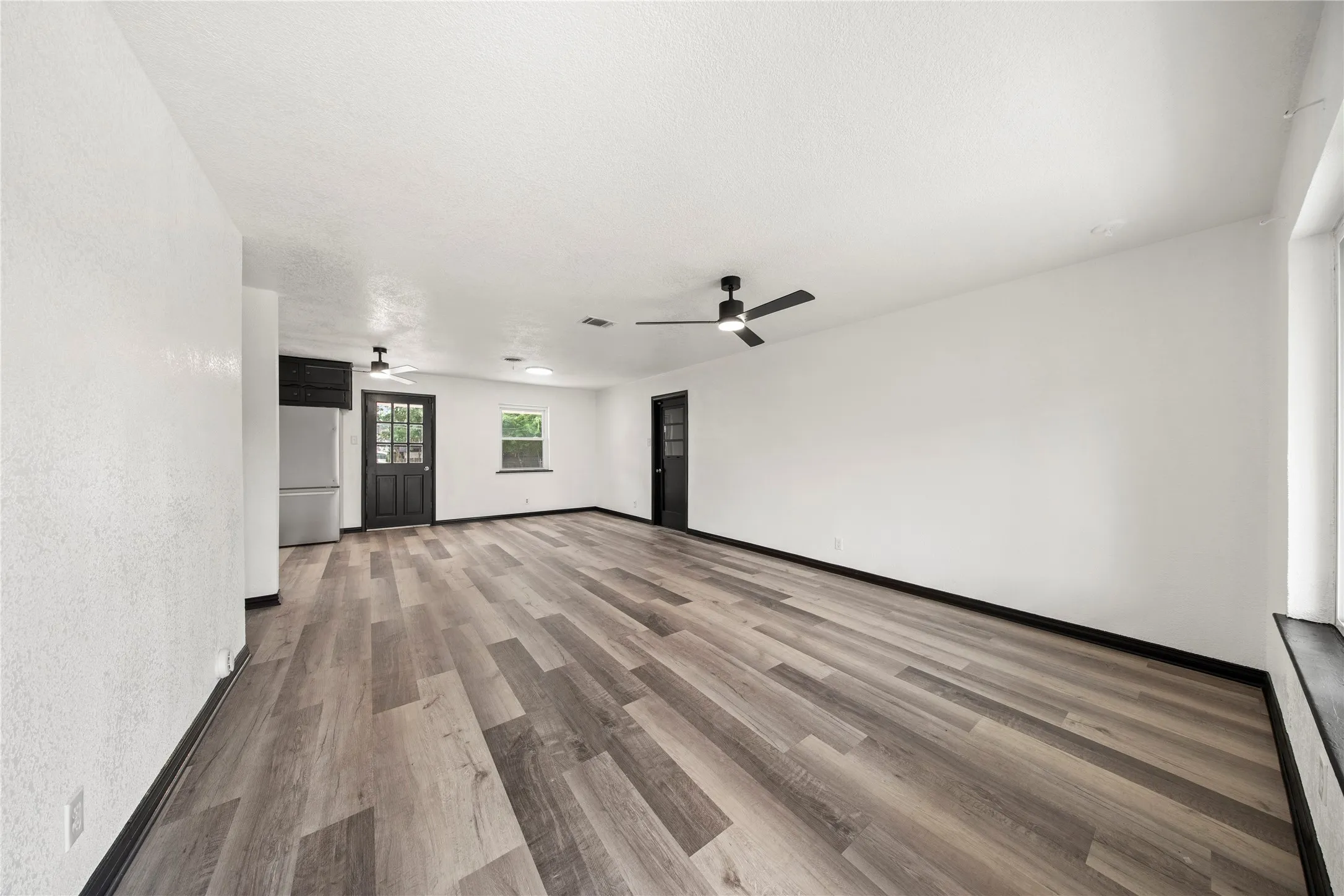 Wood-finish flooring, white painted walls, and black trim