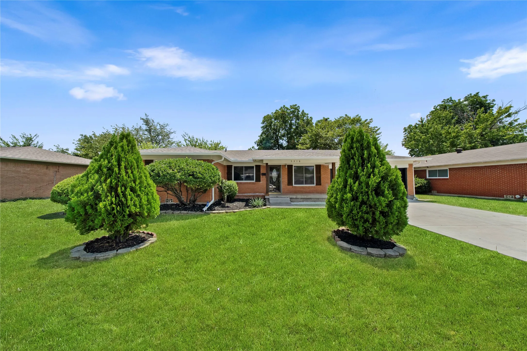 Brick exterior residence with a concrete driveway and an expansive front lawn