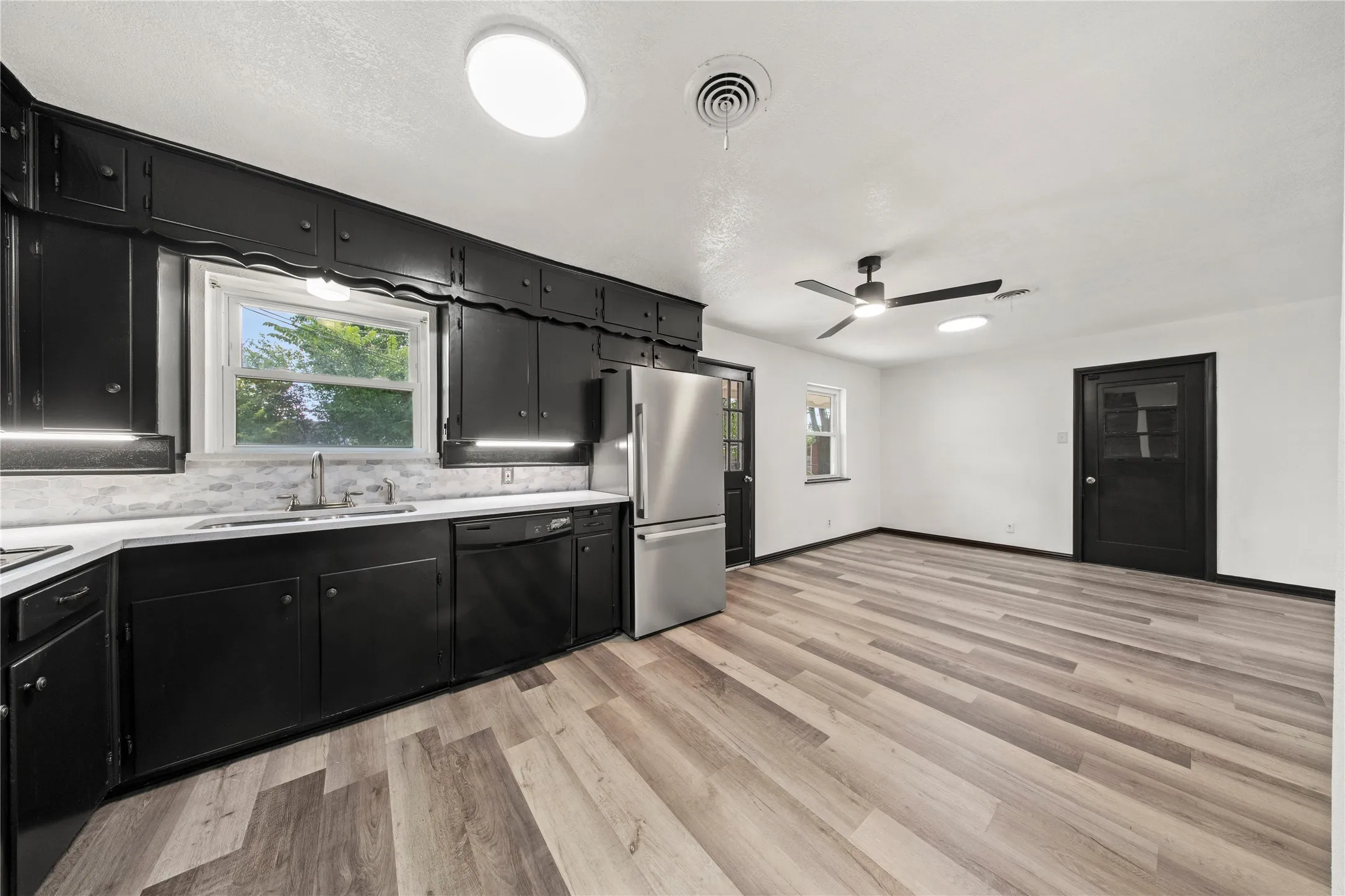 Kitchen featuring dark wood cabinetry, stainless steel appliances, a white countertop, and a tiled backsplash