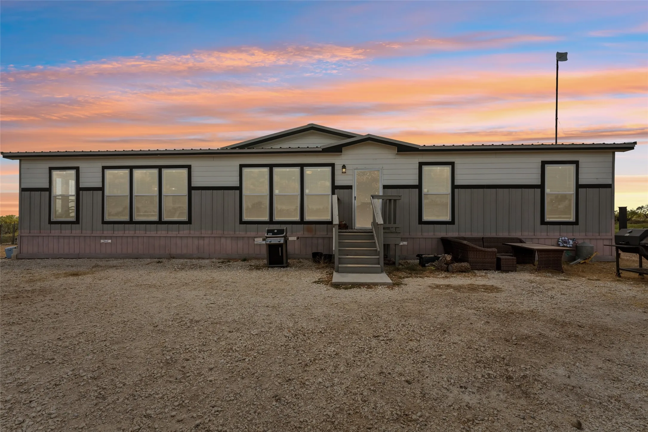 Contemporary exterior siding with horizontal and vertical paneling, multiple large windows with dark trim, and a prominent front entry with a deck and steps