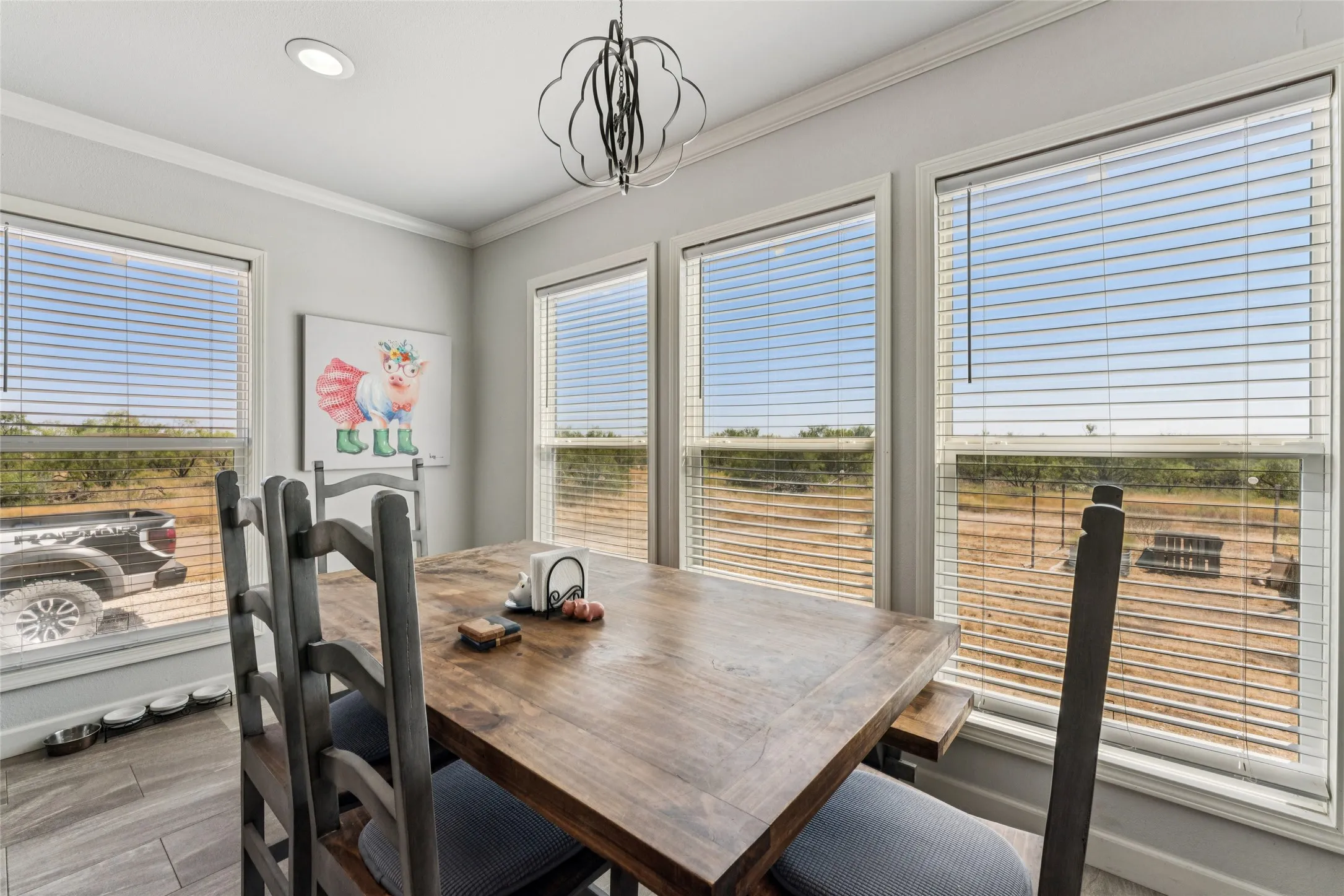 Recessed lighting and a decorative hanging fixture illuminate this space, featuring multiple windows with horizontal blinds
