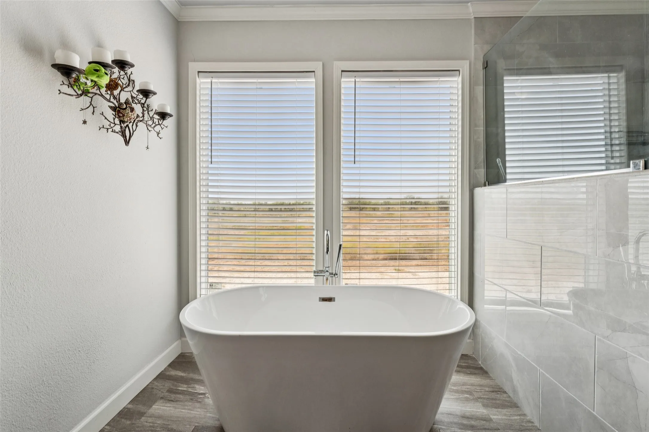 Freestanding bathtub with floor-mounted faucet, and vinyl plank flooring