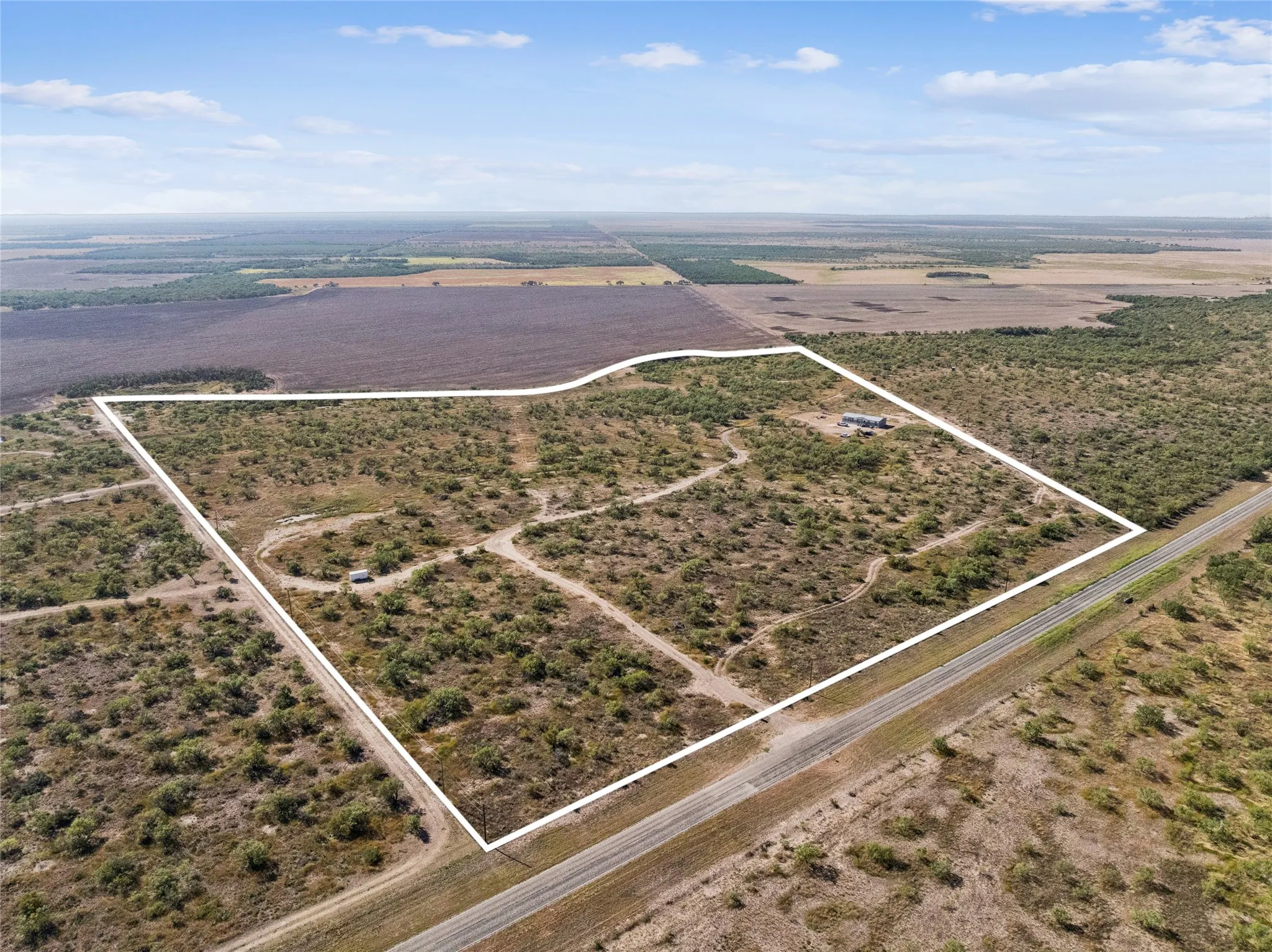 Estimated boundary lines from the NorthWest view of the expansive acreage featuring a single-story residence, natural vegetation, one tank/pond, an abundance of wildlife and direct road frontage