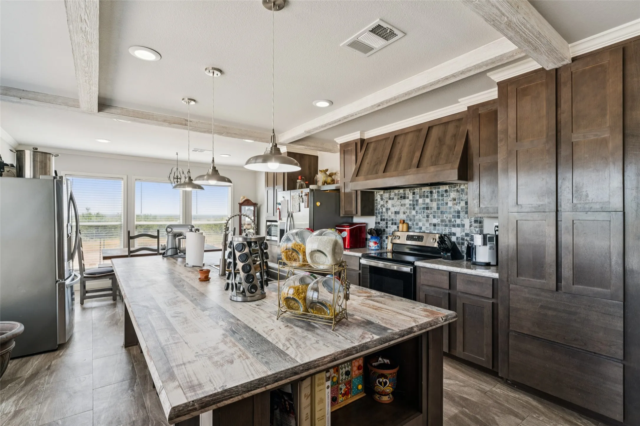 Kitchen featuring an expansive island with stainless steel appliances, dark wood cabinetry, a tile backsplash, and recessed lighting