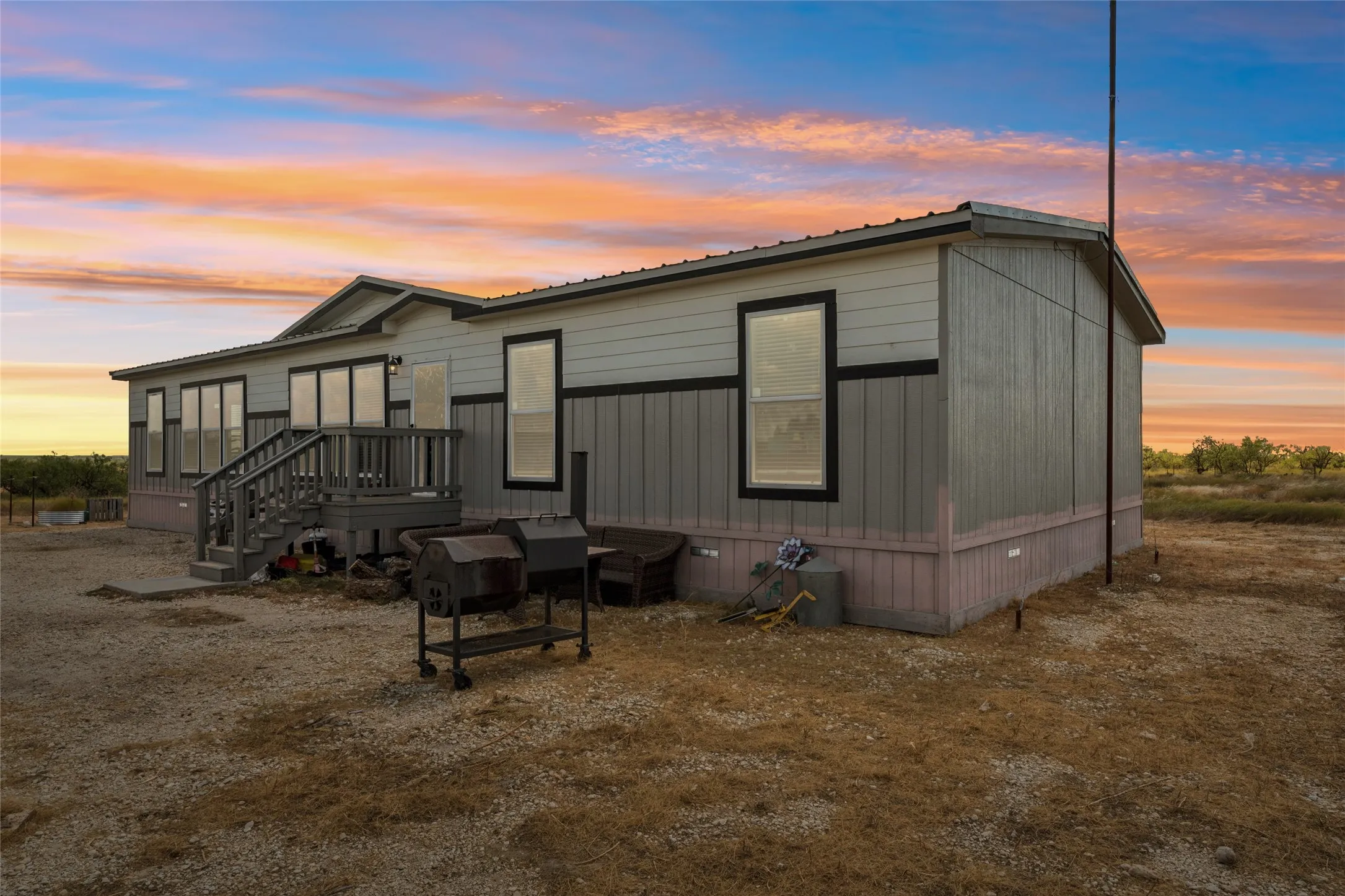 Exterior featuring horizontal siding and vertical paneling, elevated entry deck with stairs, multiple windows with dark trim, and a metal roof