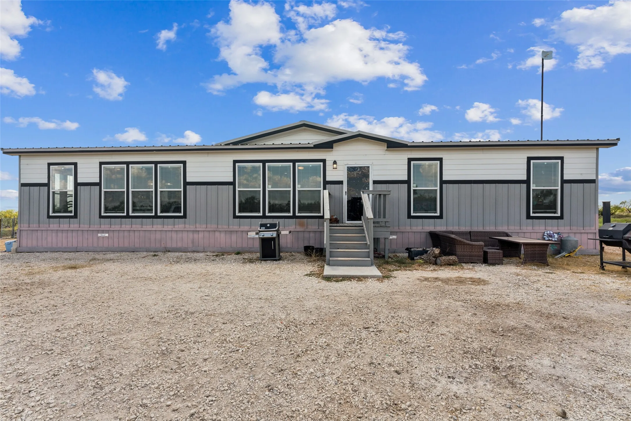 Contemporary exterior with horizontal and vertical siding, multiple large windows with dark trim, an elevated entry porch with steps, and a metal roof