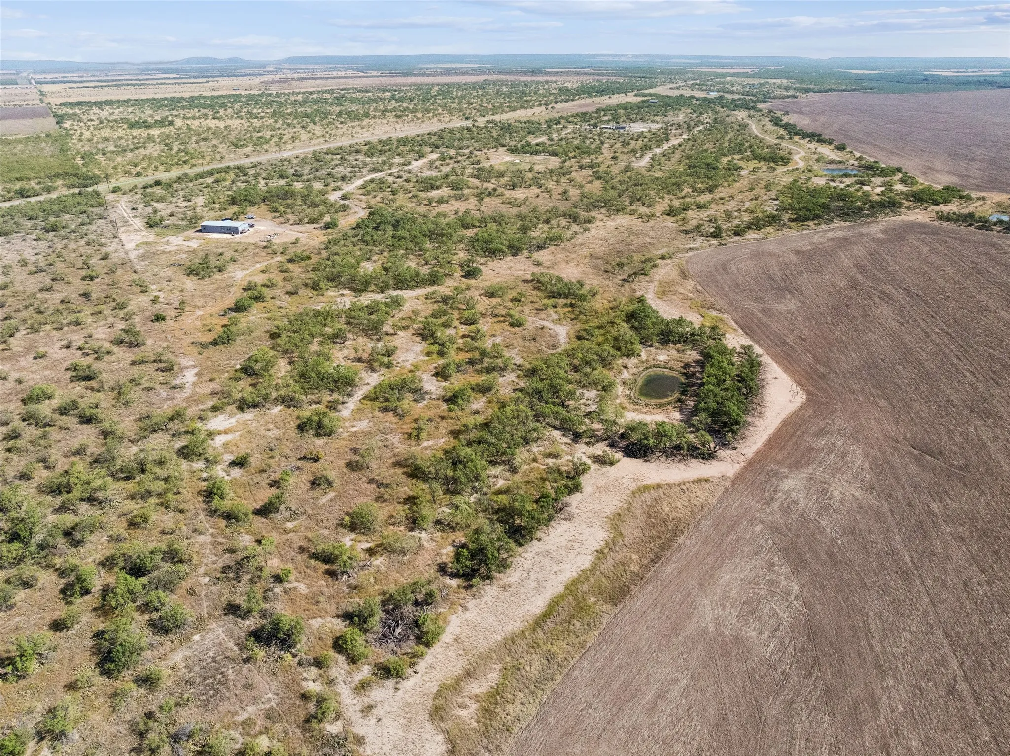View from the SouthEast corner of the expansive land parcel featuring natural vegetation, and tank/pond