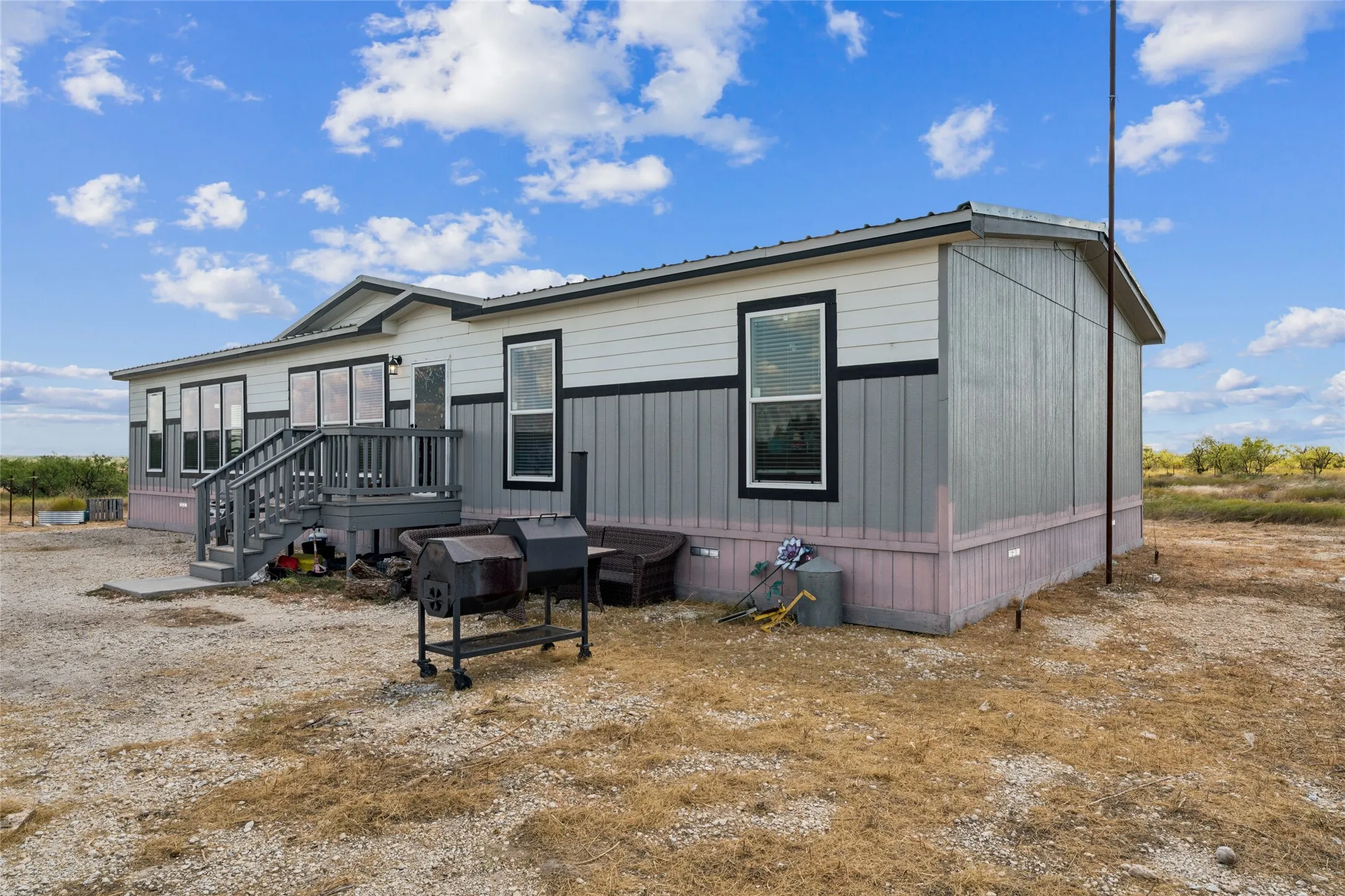 Multipanel siding exterior with contrasting trim, elevated wood-finish deck with railings, and multiple windows