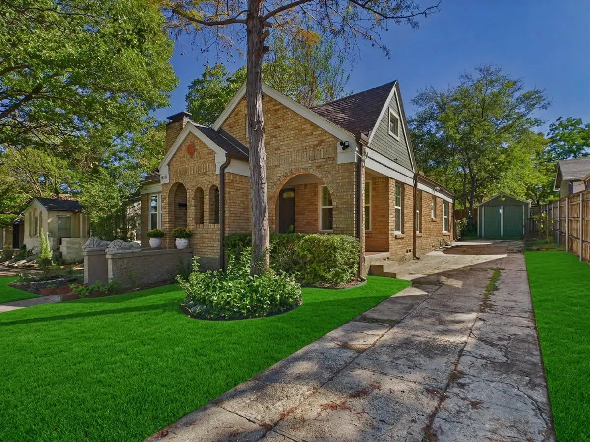 Brick exterior with arched entryways, gabled roofline, and established landscaping