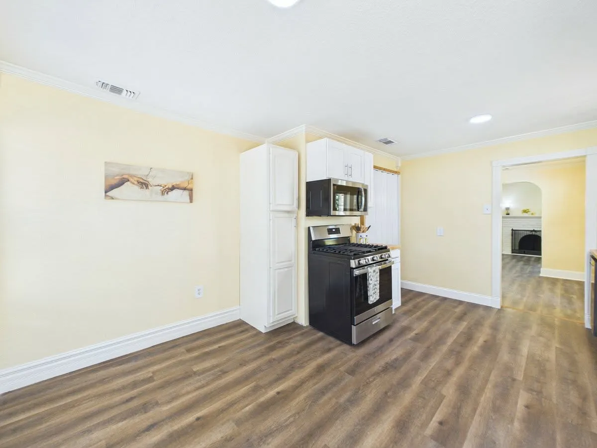 Wood-finish flooring throughout, white upper and lower cabinetry, stainless steel range, and built-in microwave