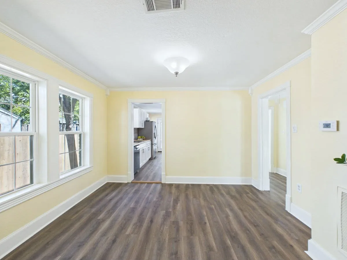 Spacious room featuring wood-finish flooring, multiple windows, and crown molding
