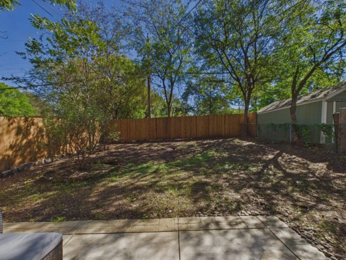Expansive outdoor space featuring a concrete patio, wood privacy fencing, and mature trees