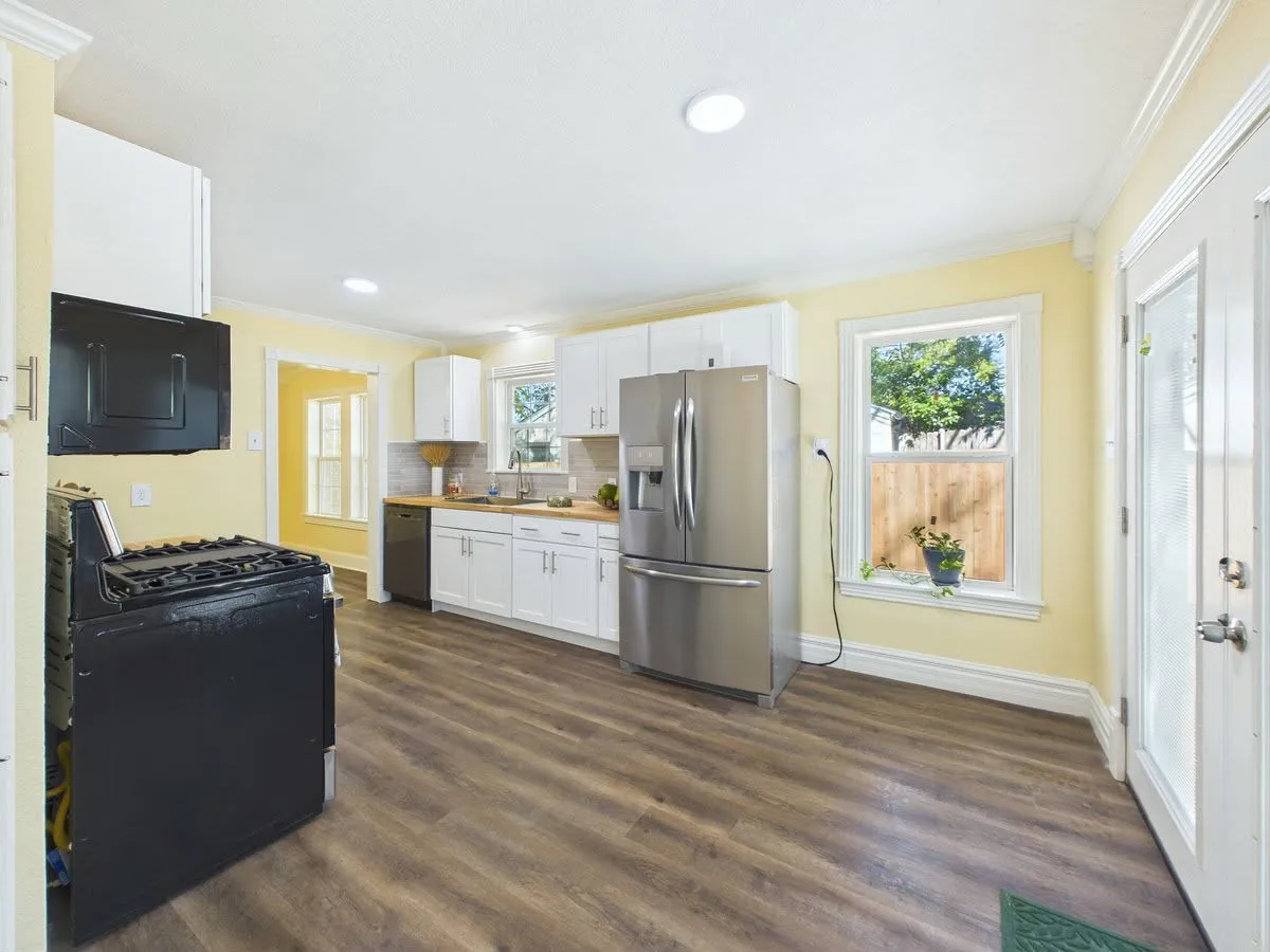 Kitchen featuring wood-finish flooring, white cabinetry, recessed lighting, stainless steel refrigerator, and a built-in dishwasher