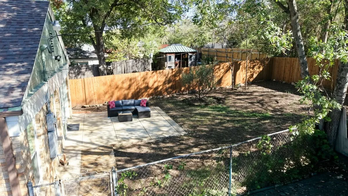 Expansive backyard featuring a new privacy fence, mature trees, and a spacious patio area