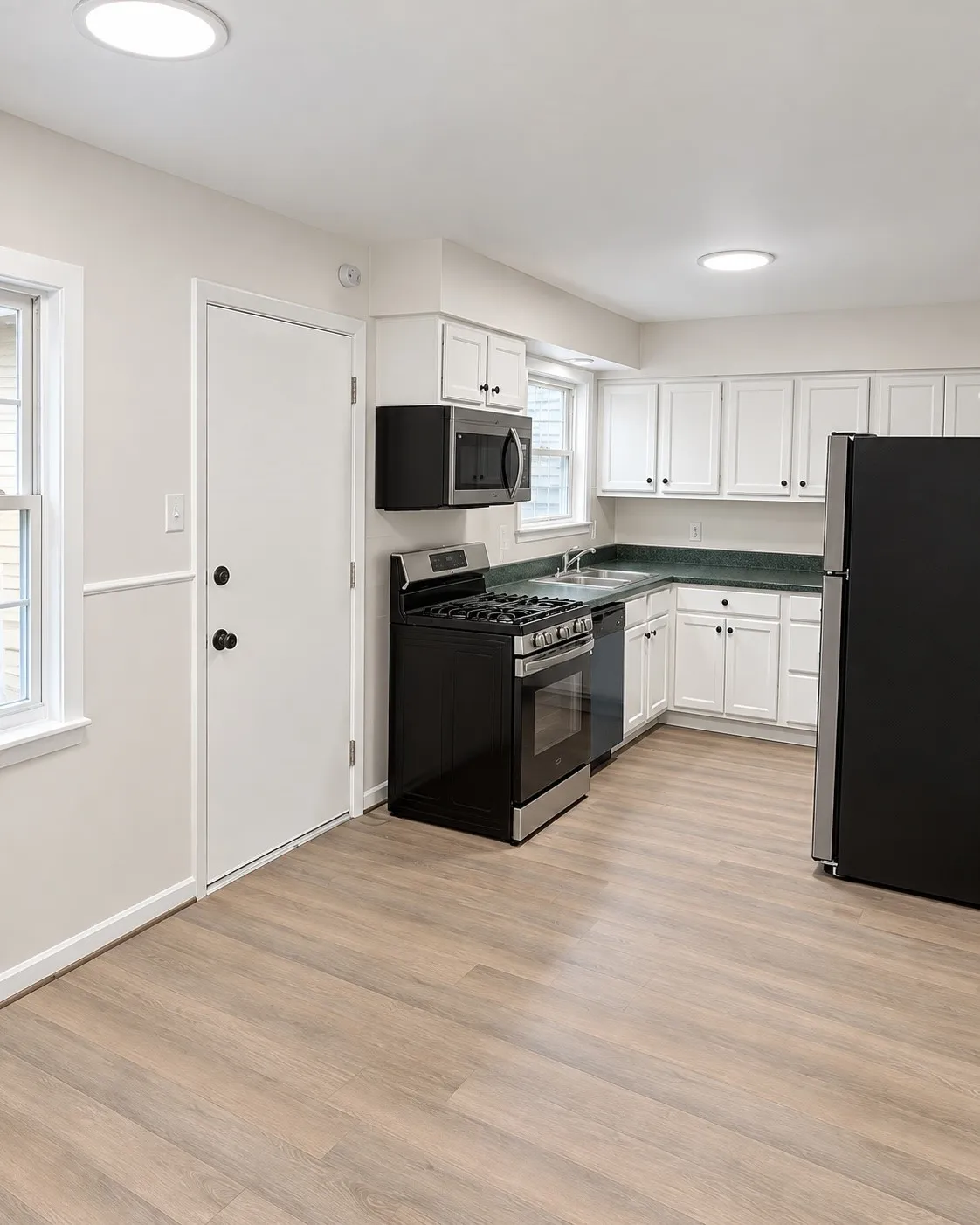 Kitchen featuring wood-finish flooring, white cabinetry, a stainless steel microwave, and a black range
