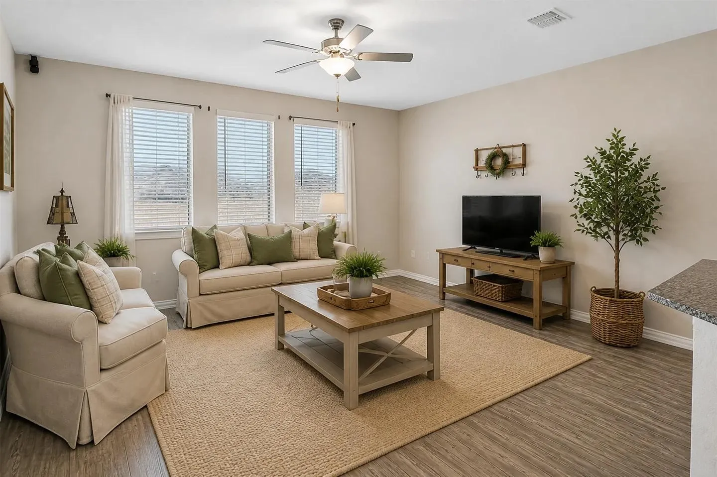 Virtually Staged
Three large windows, wood-finish flooring, light-toned walls, and a ceiling fan with integrated lighting