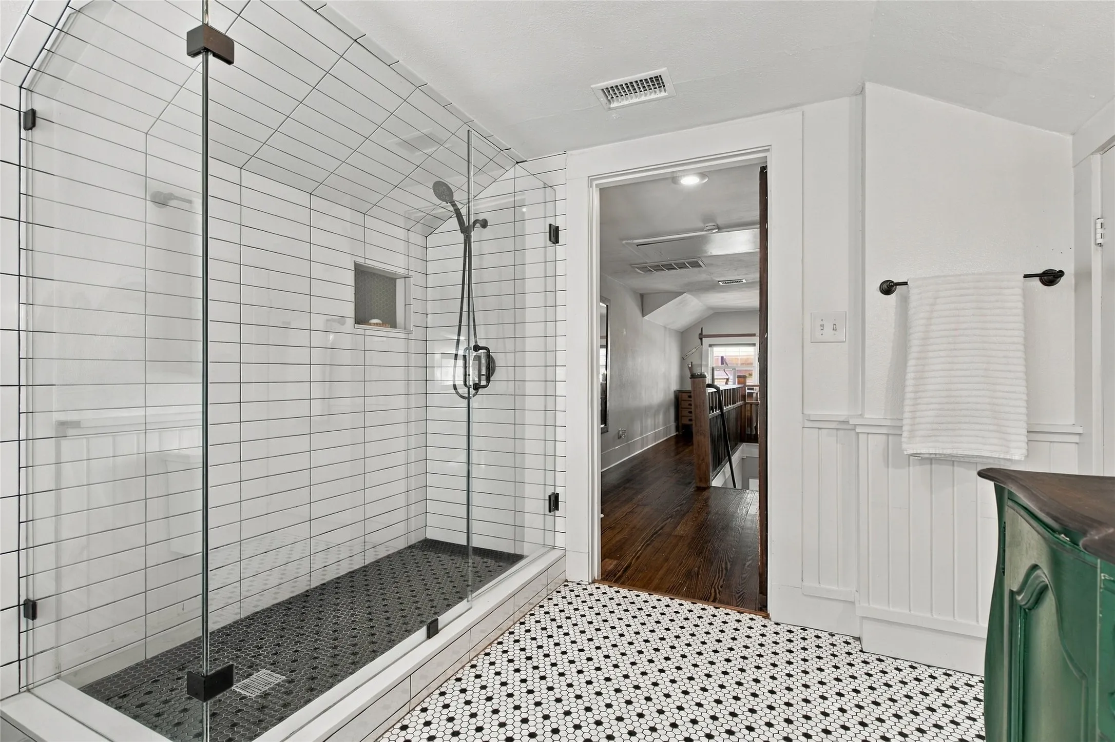 Glass-enclosed shower with subway tile surround and dark tile base