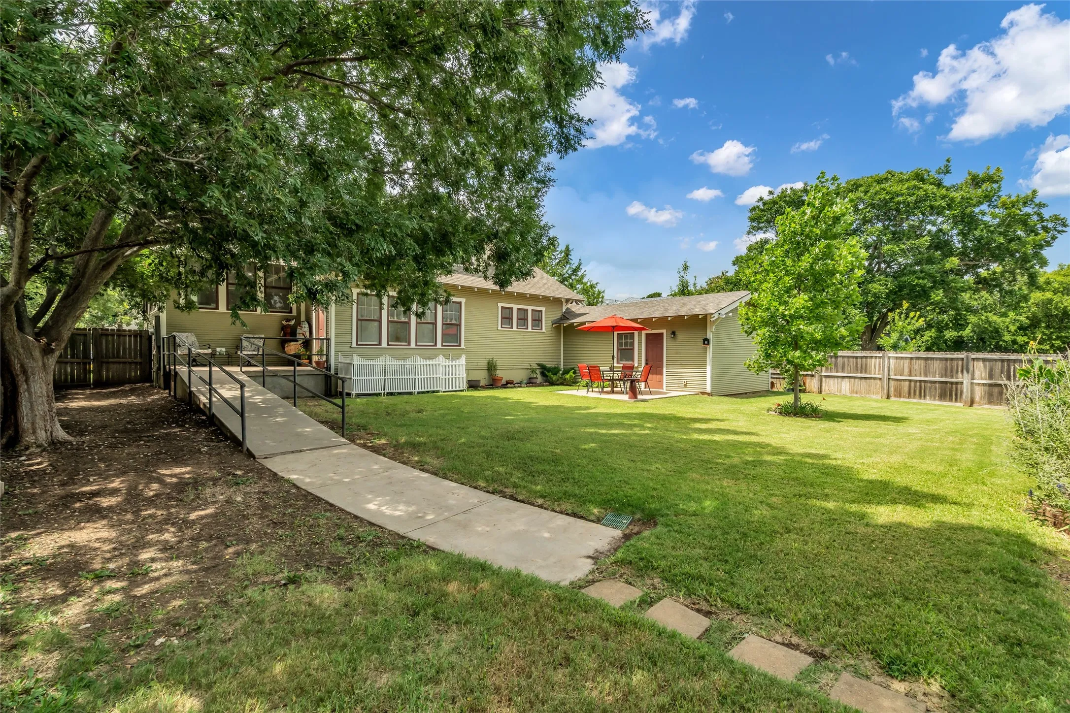 Expansive lawn with mature trees and wood fence