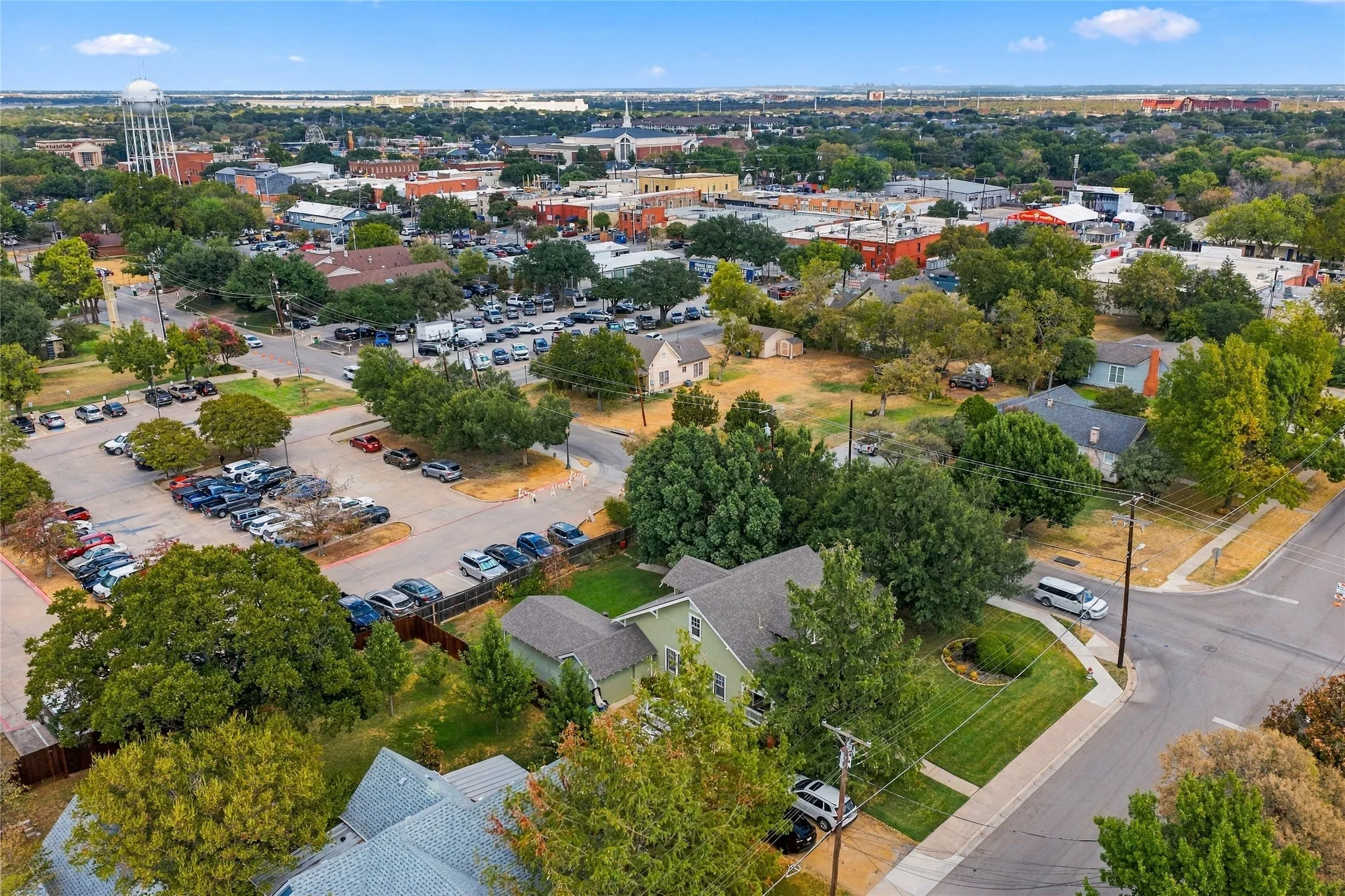 Aerial view showcasing a residential property with mature landscaping, manicured lawn, and detached garage situated on a tree-lined lot