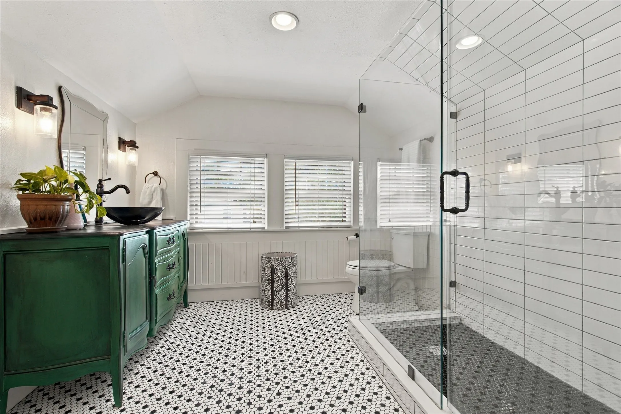 Glass-enclosed shower with subway tile surround, patterned floor tiling, green vanity with vessel sink, and recessed lighting