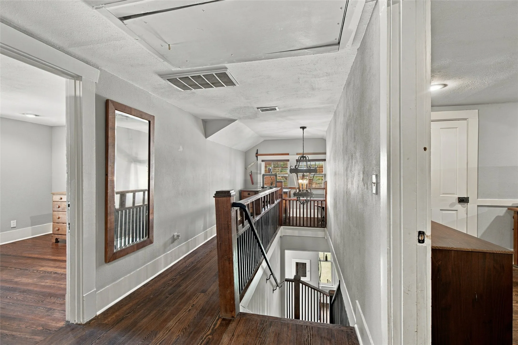 Hardwood flooring, painted walls, white trim, attic access, and a second-story railing