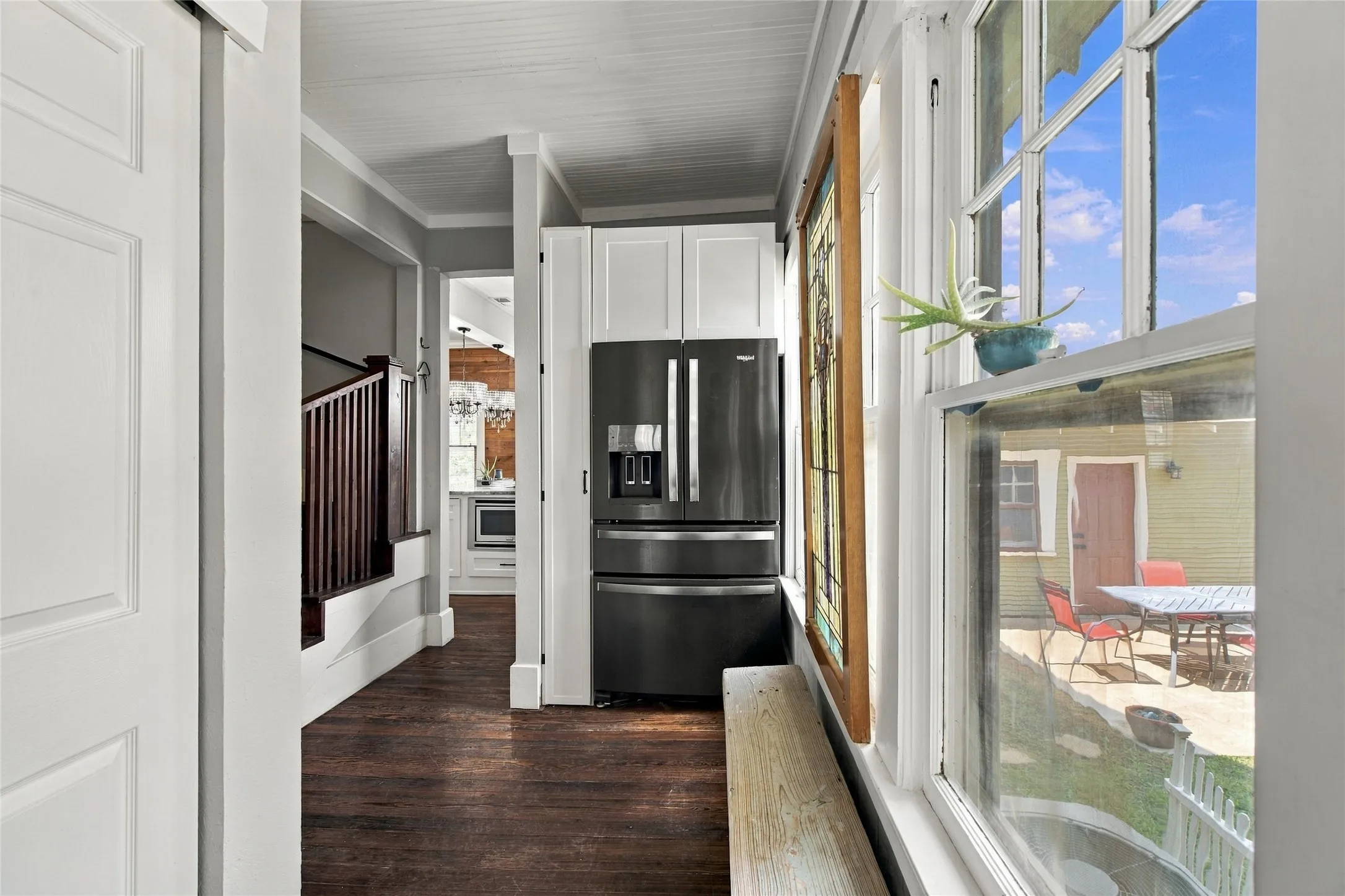 Hardwood flooring, white cabinetry, dark stainless steel refrigerator, stained glass art, multi-pane windows