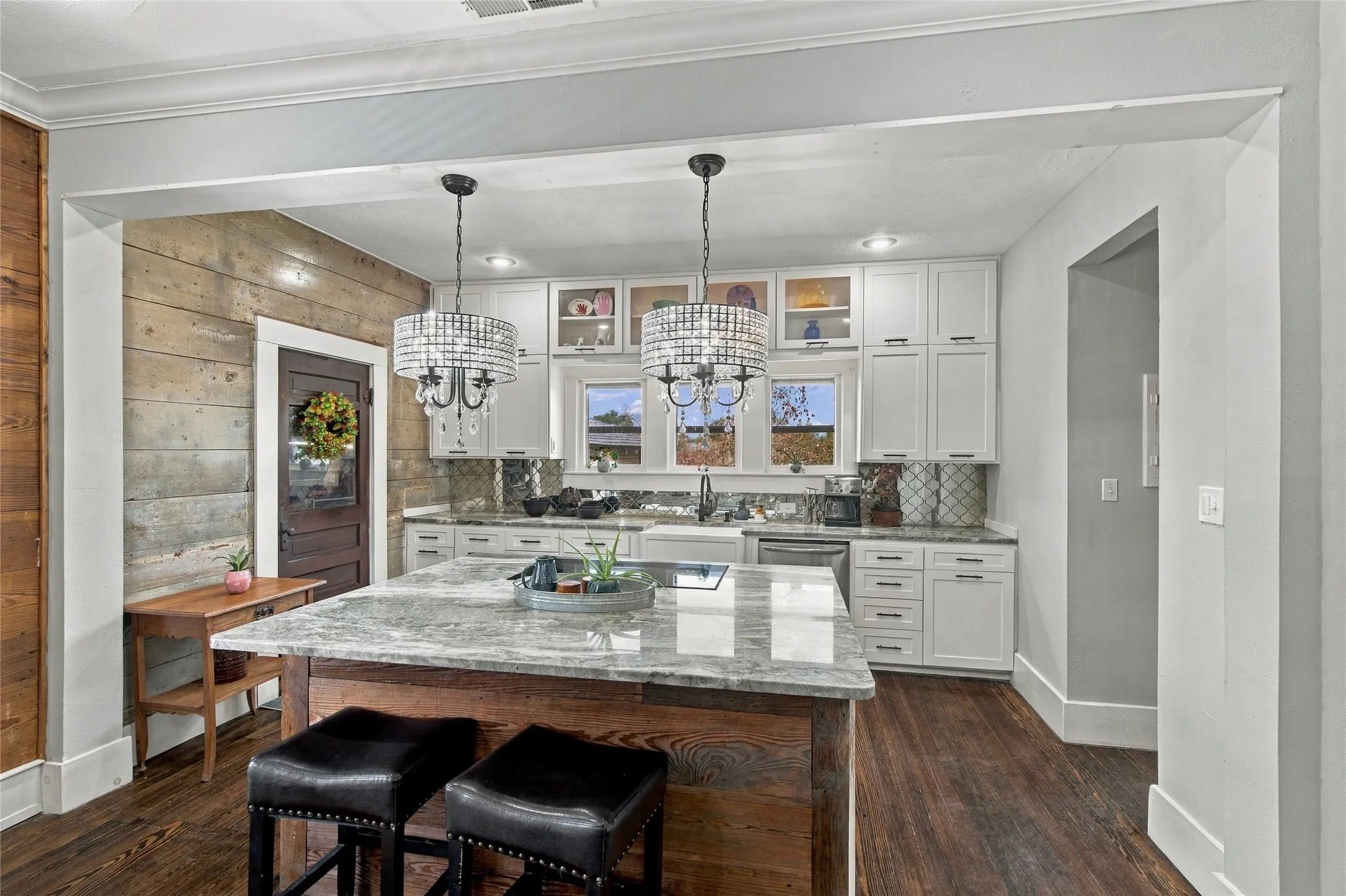 The kitchen's large island is the heart of the kitchen. Multiple windows overlook the backyard.