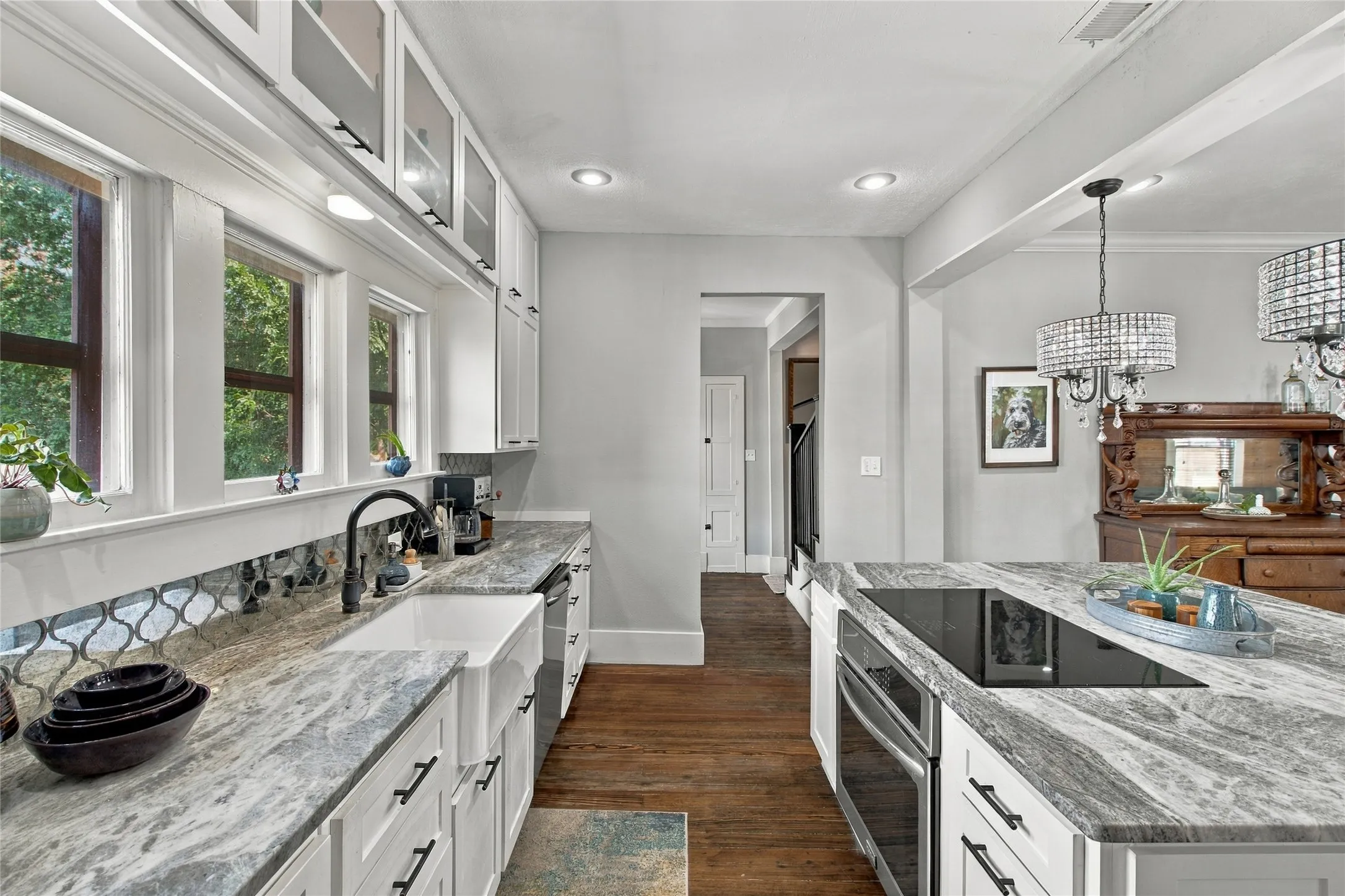 The white cabinetry, farmhouse sink, mirrored backsplash and windows provide a welcoming place for food prep.