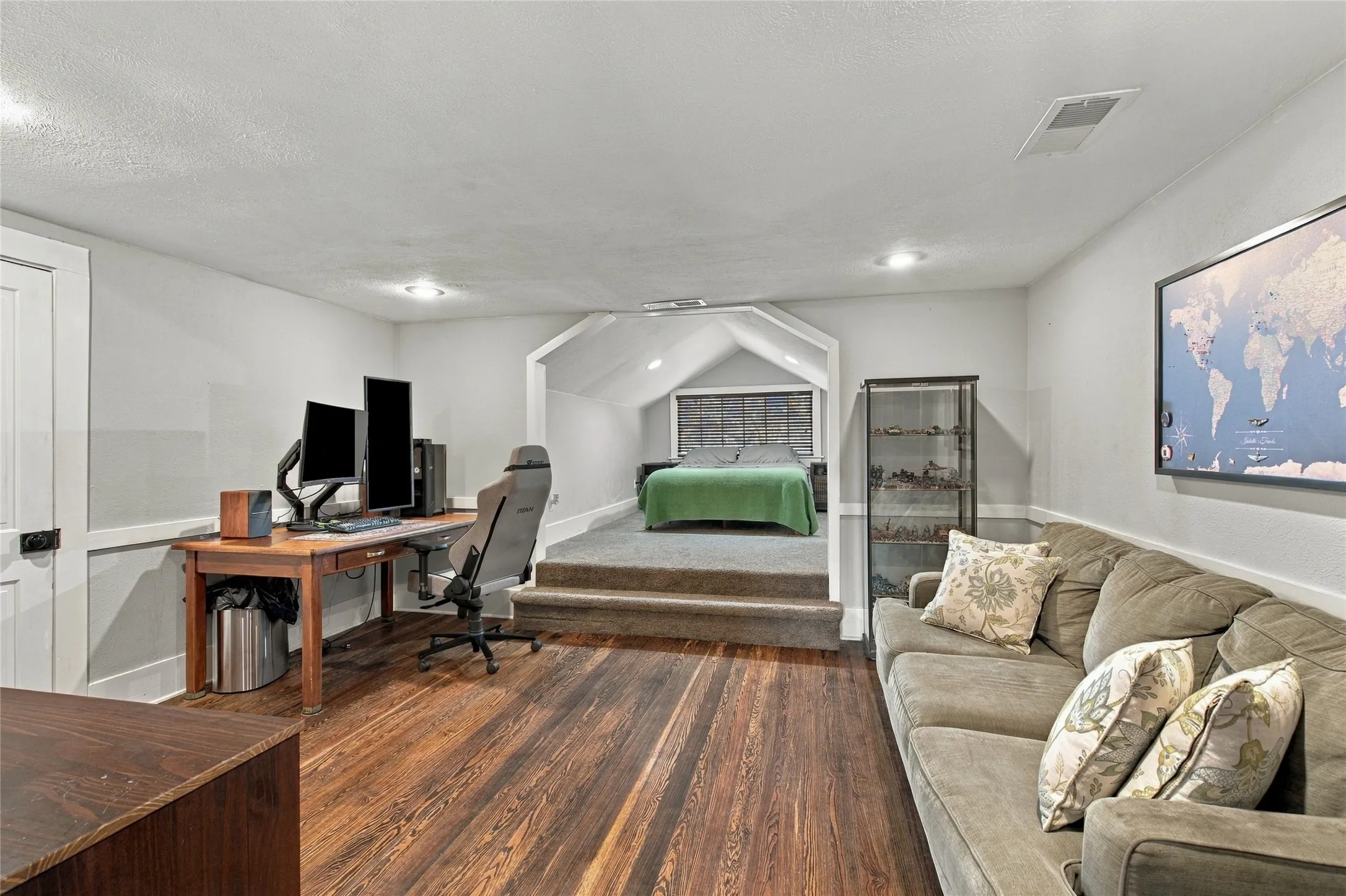 Hardwood flooring throughout the main area, with a carpeted raised platform