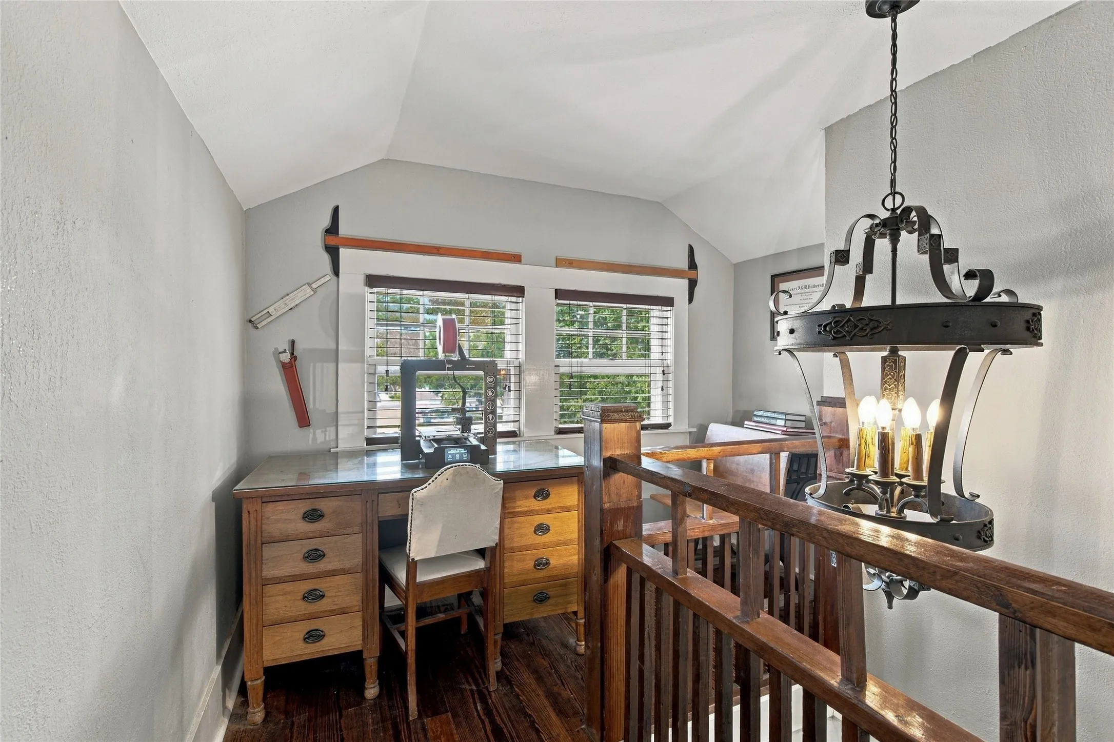 Wood-finish flooring, built-in shelving, windows with blinds, and a wrought iron chandelier