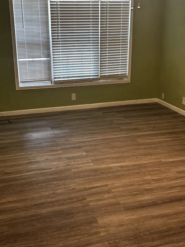 Wood-finish flooring with a horizontal window featuring blinds