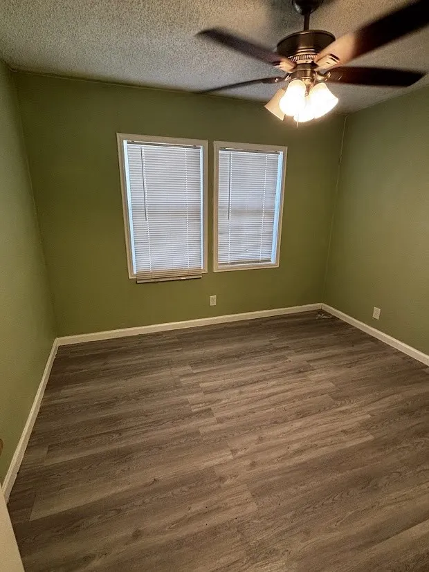 Wood-finish flooring, dual windows, ceiling fan with integrated lighting, and neutral wall paint