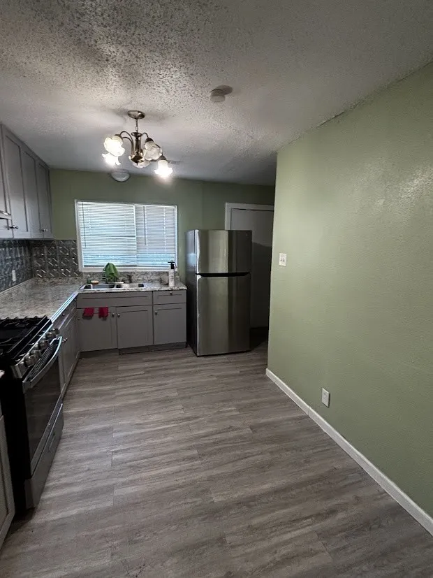 Kitchen featuring wood-finish flooring, a stainless steel refrigerator, and a gas range