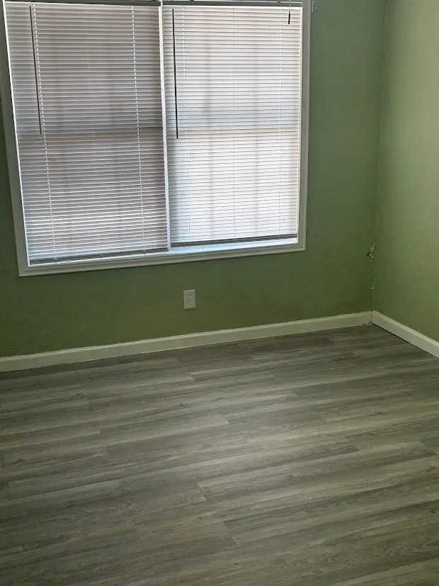 Wood-finish flooring with white trim and a double window