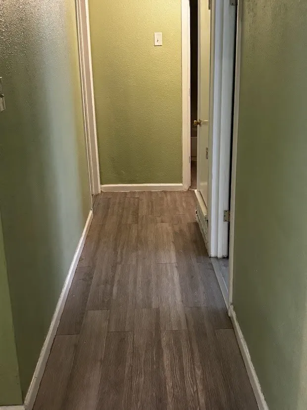 Wood-finish flooring with light green wall tones and white trim