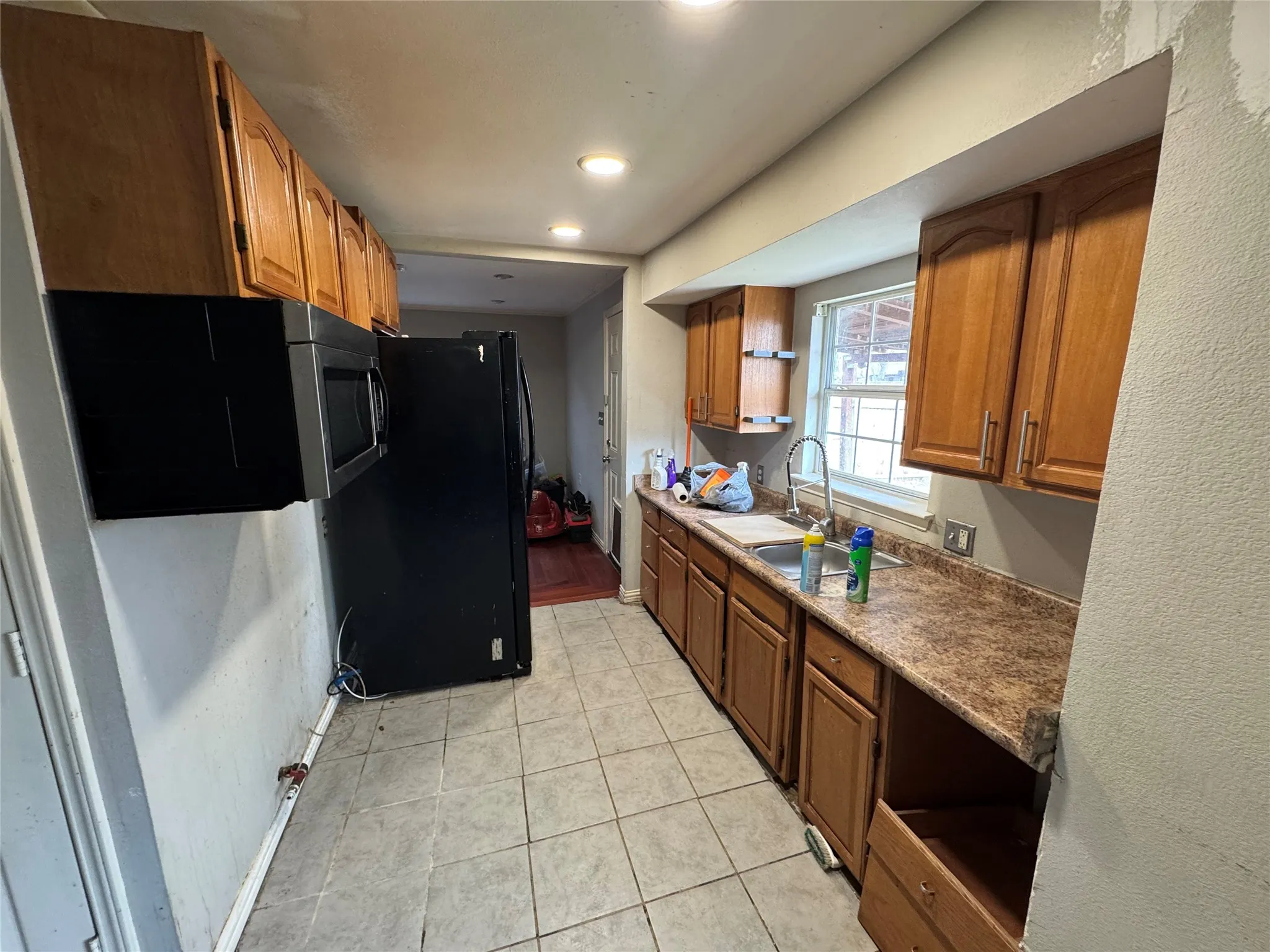 Kitchen featuring wood cabinetry, tiled flooring, built-in microwave, and a stainless steel sink with a single-handle faucet