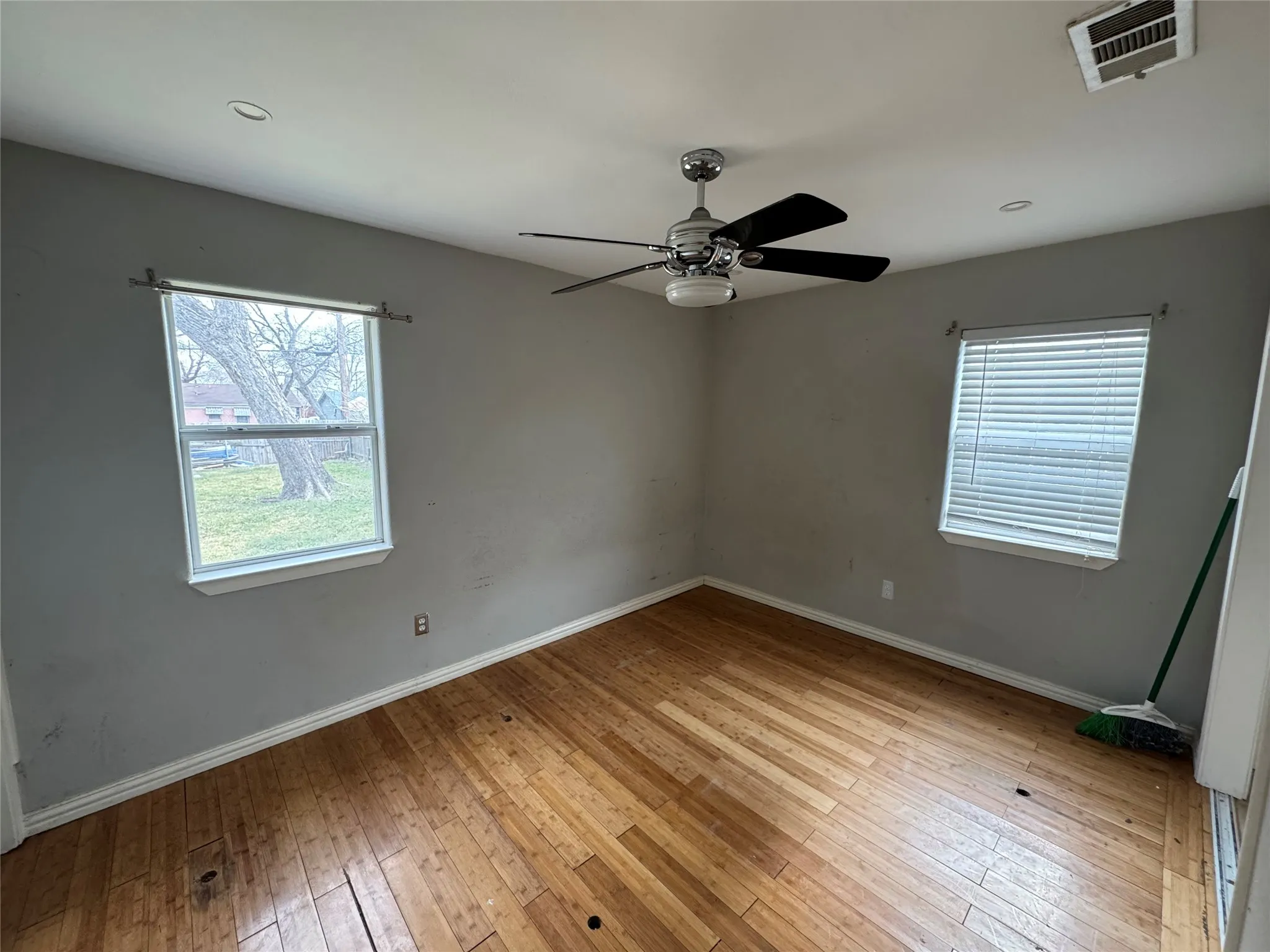 Wood-finish flooring, ceiling fan with integrated lighting, recessed ceiling lighting, and multiple windows