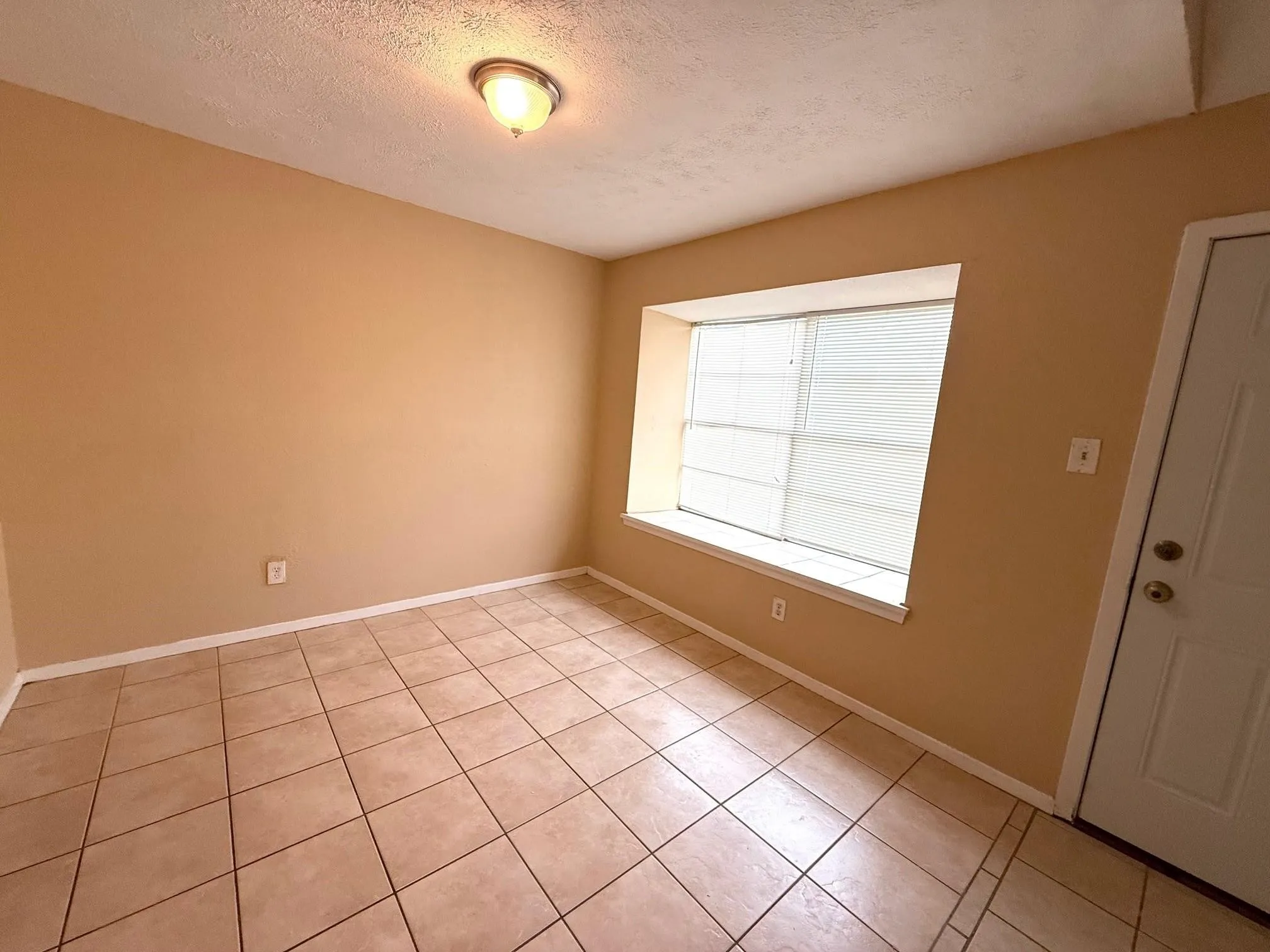 Tile flooring, neutral wall tones, window with horizontal blinds, and a ceiling-mounted light fixture