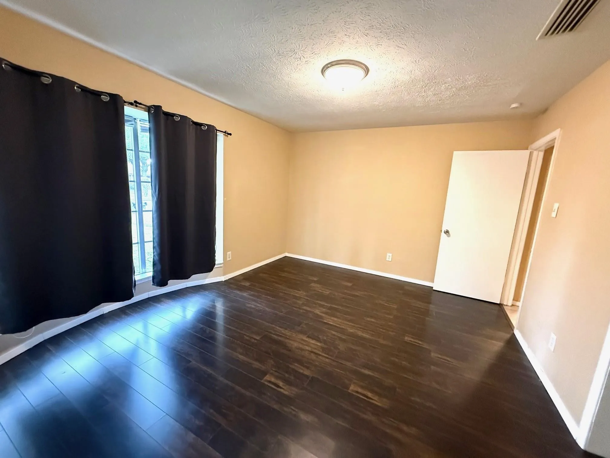 Wood-finish flooring with a smooth finish, neutral wall tones, and recessed lighting