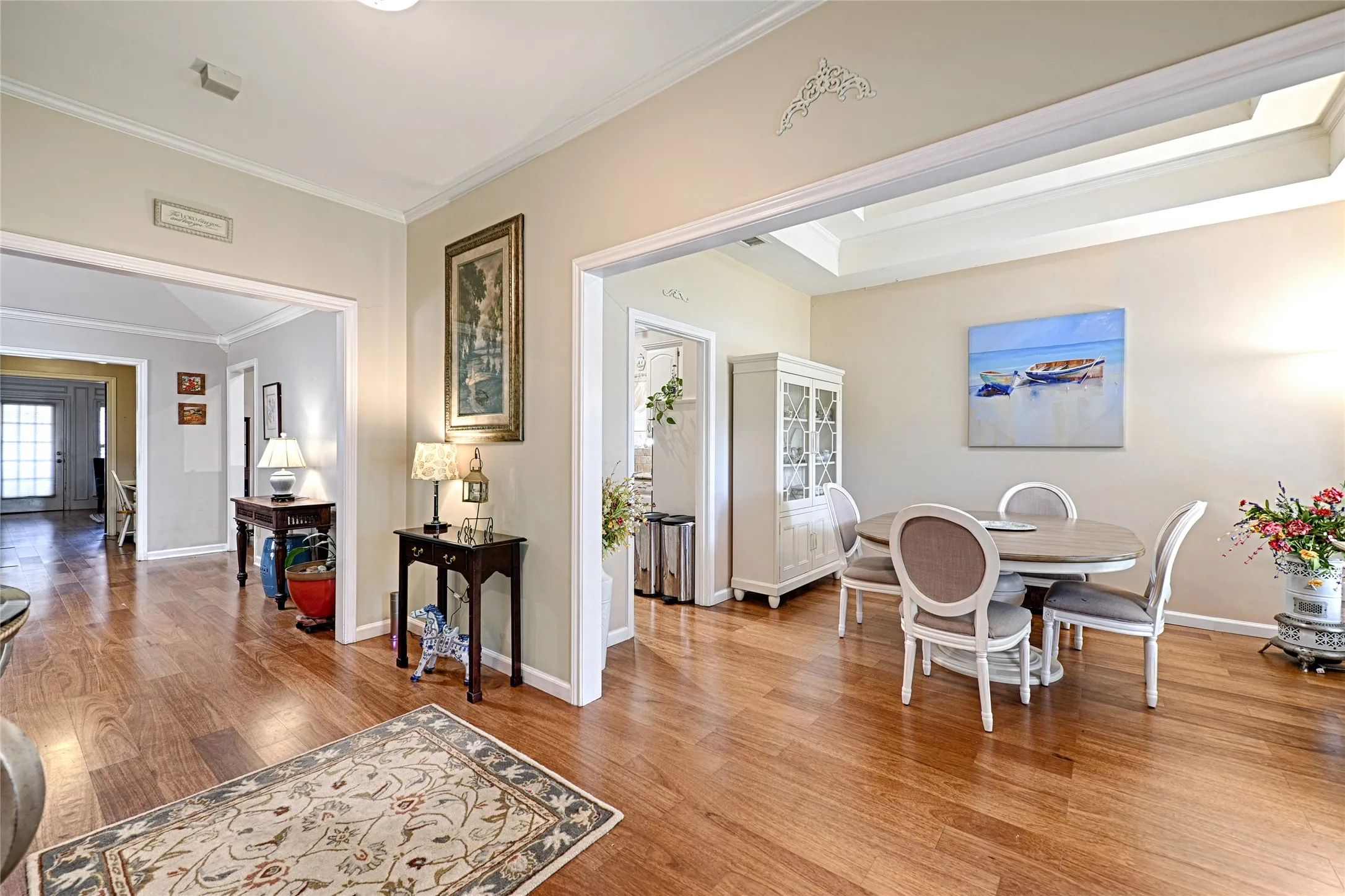 Warm wood-finish flooring throughout, tray ceiling with decorative molding, and recessed lighting