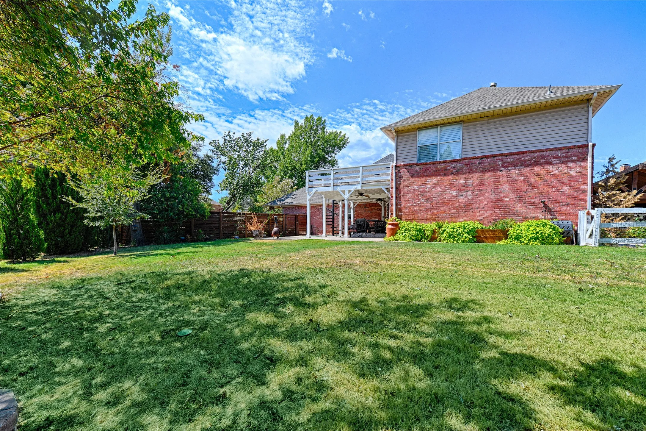 Expansive lawn featuring mature trees and a multi-level deck with a covered patio